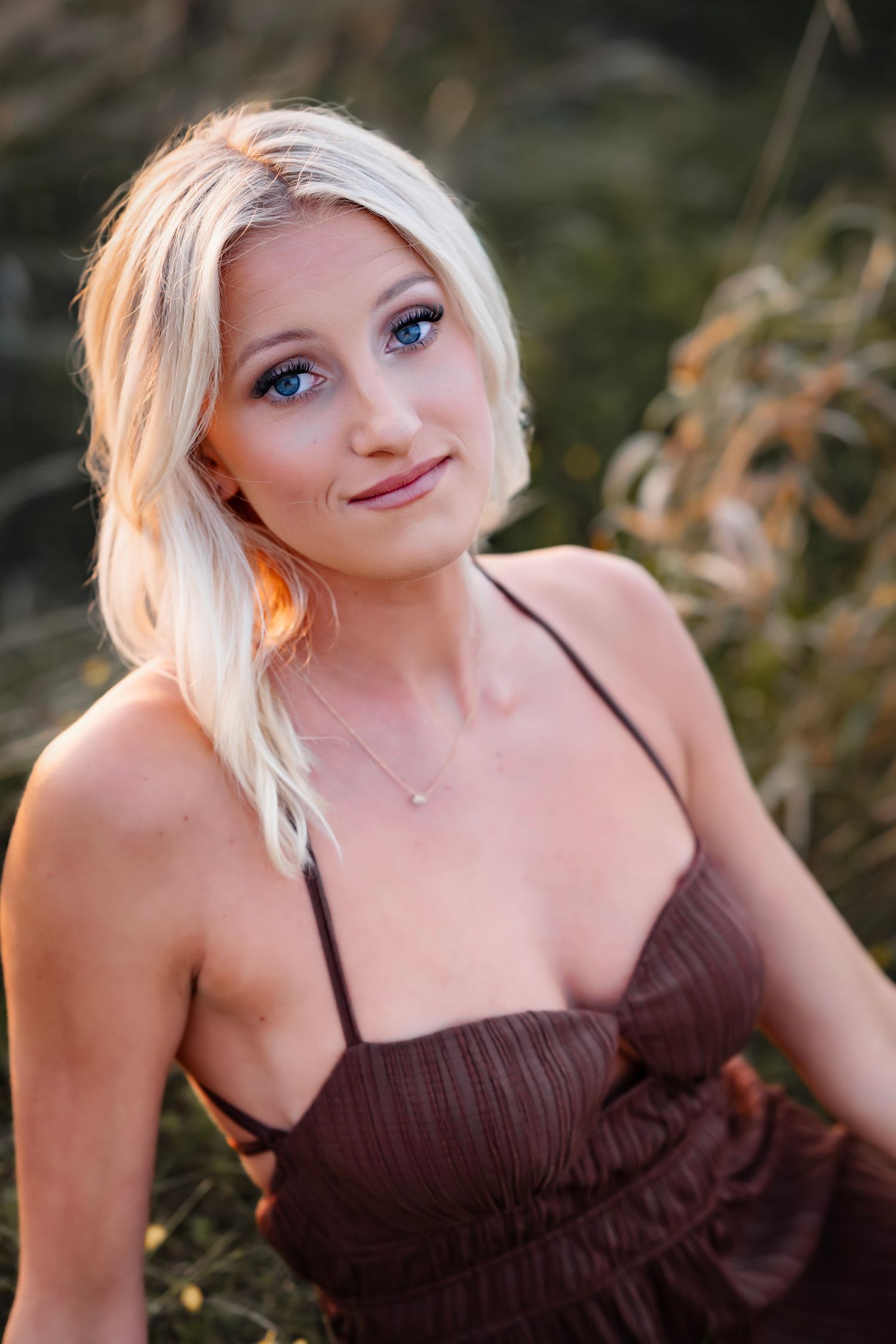 Woman with blonde hair wearing a brown dress poses outdoors in a series of close-up portrait shots.