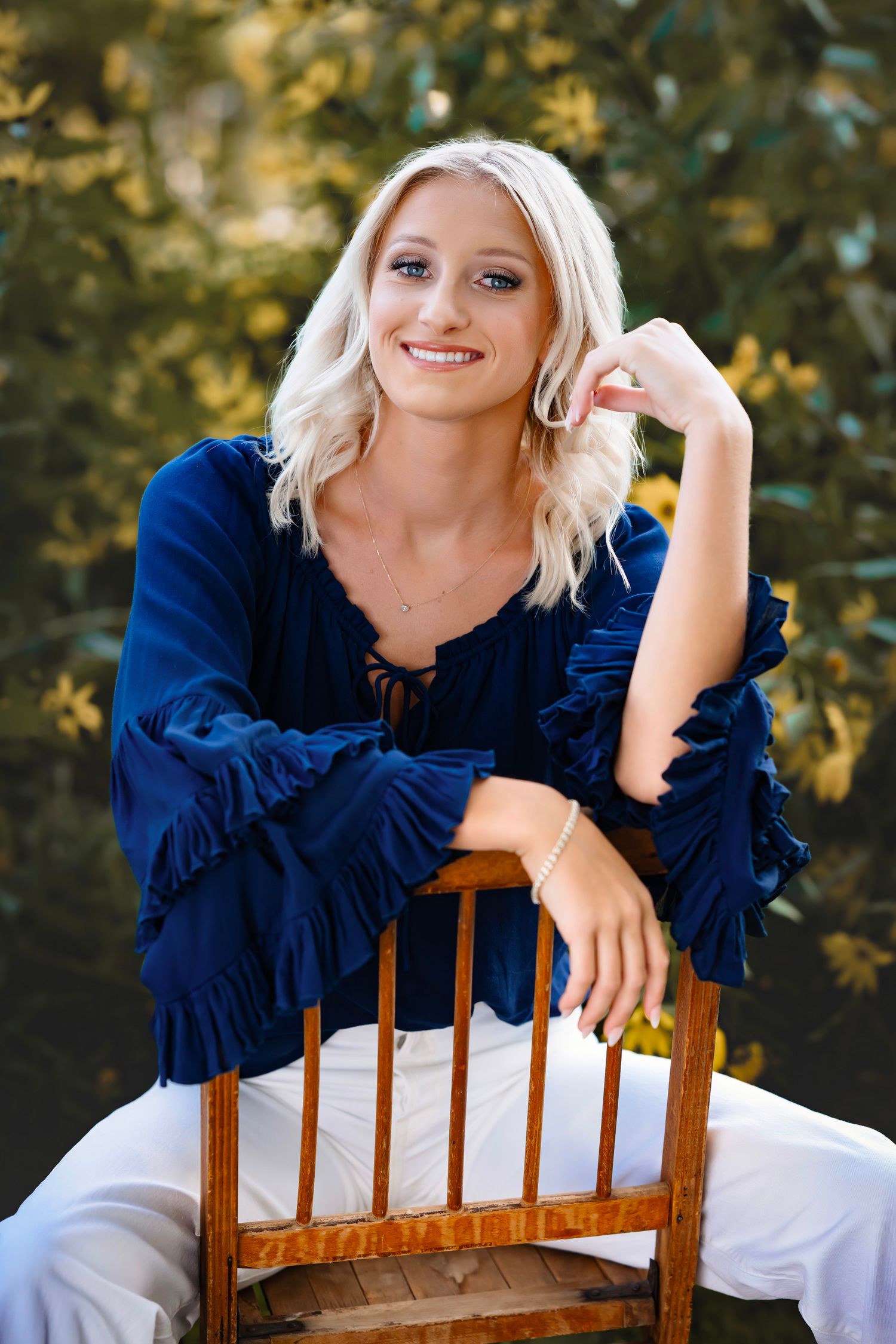 A series of outdoor portrait photos showing someone in a navy blue ruffled top posing on a wooden chair.