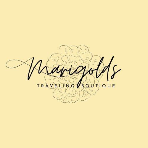 Logo for Marigolds Traveling Boutique featuring elegant script text over a detailed marigold flower illustration on pale yellow.