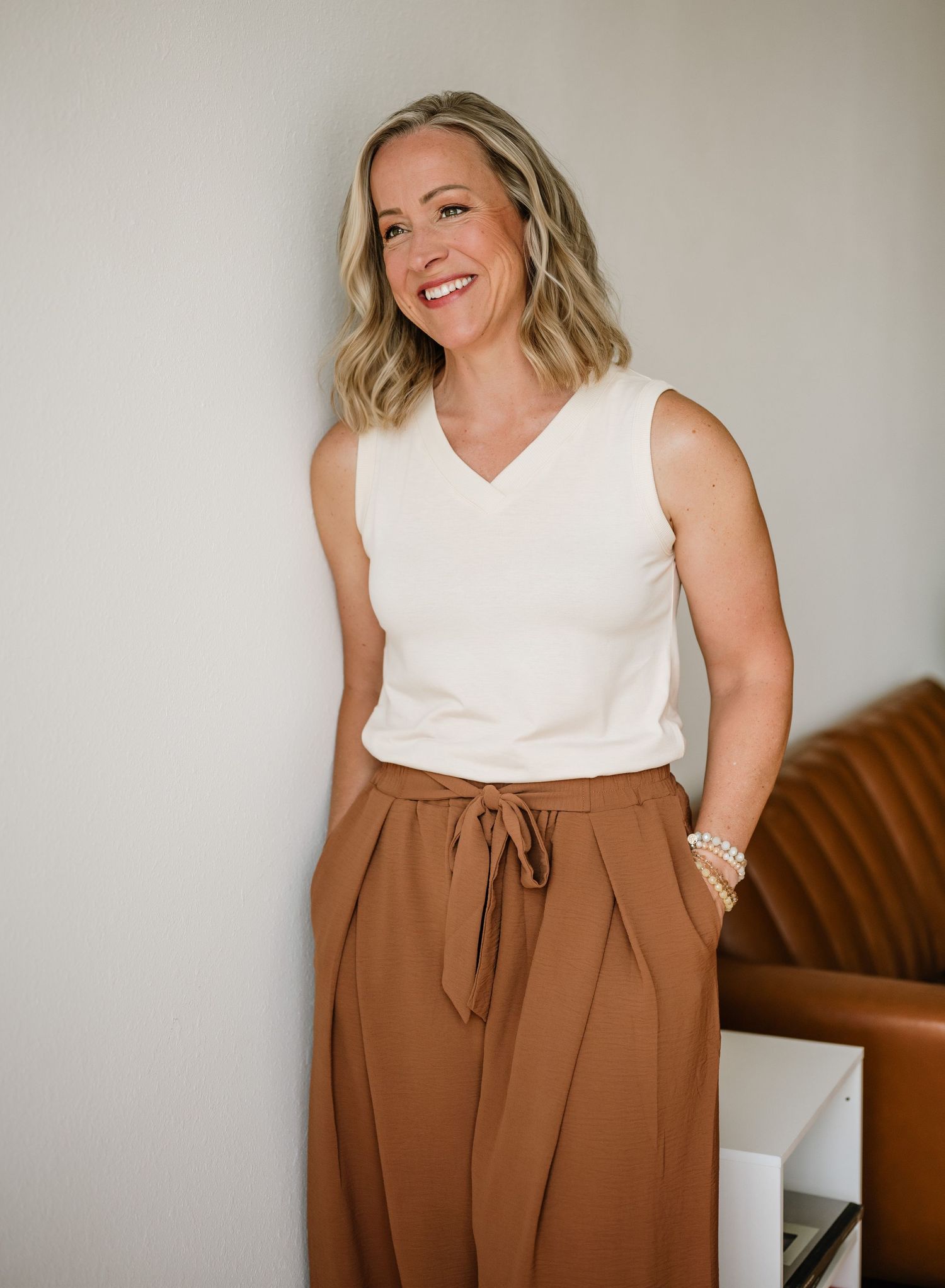 Professional fashion photo series showing white sleeveless top paired with stylish brown high-waisted pants.
