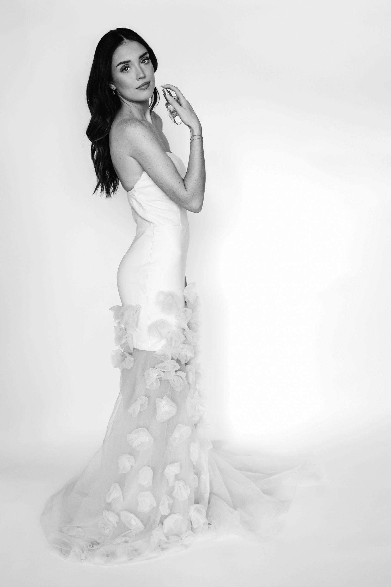 A fashion photoshoot series showing a model in an elegant white dress with flowy ruffled details against a light background.