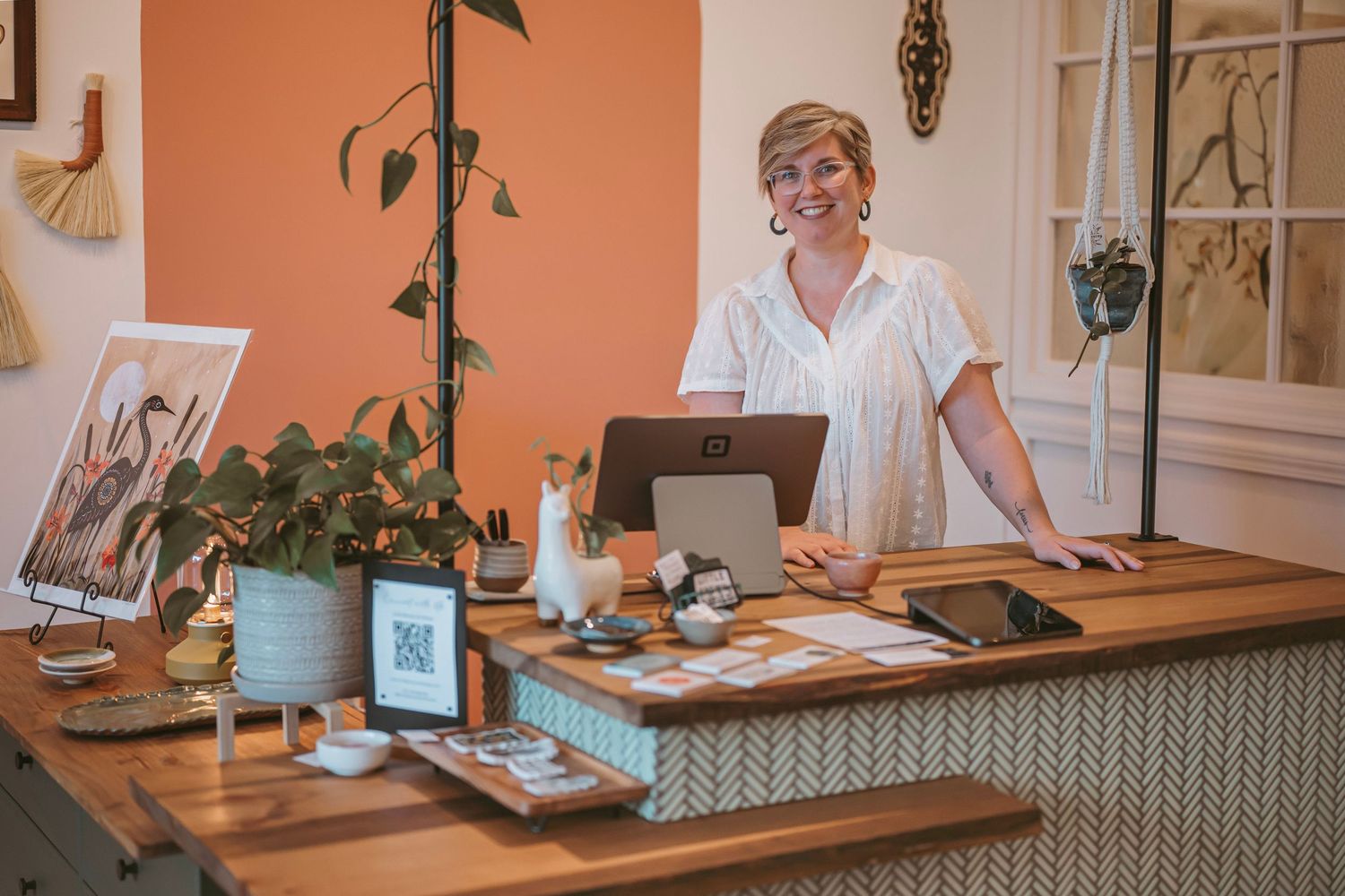 Professional at work in a bright office space with peach-colored walls and decorative plants.