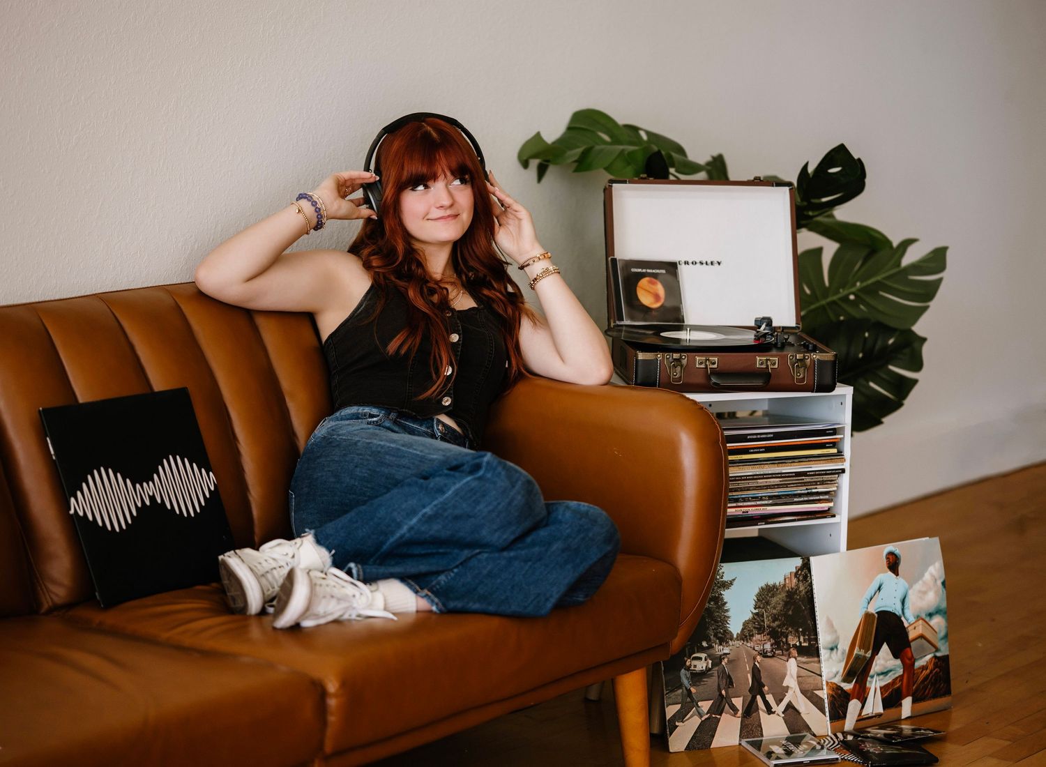 A person relaxes on a brown leather couch with shoes displayed on the floor in a modern living space.
