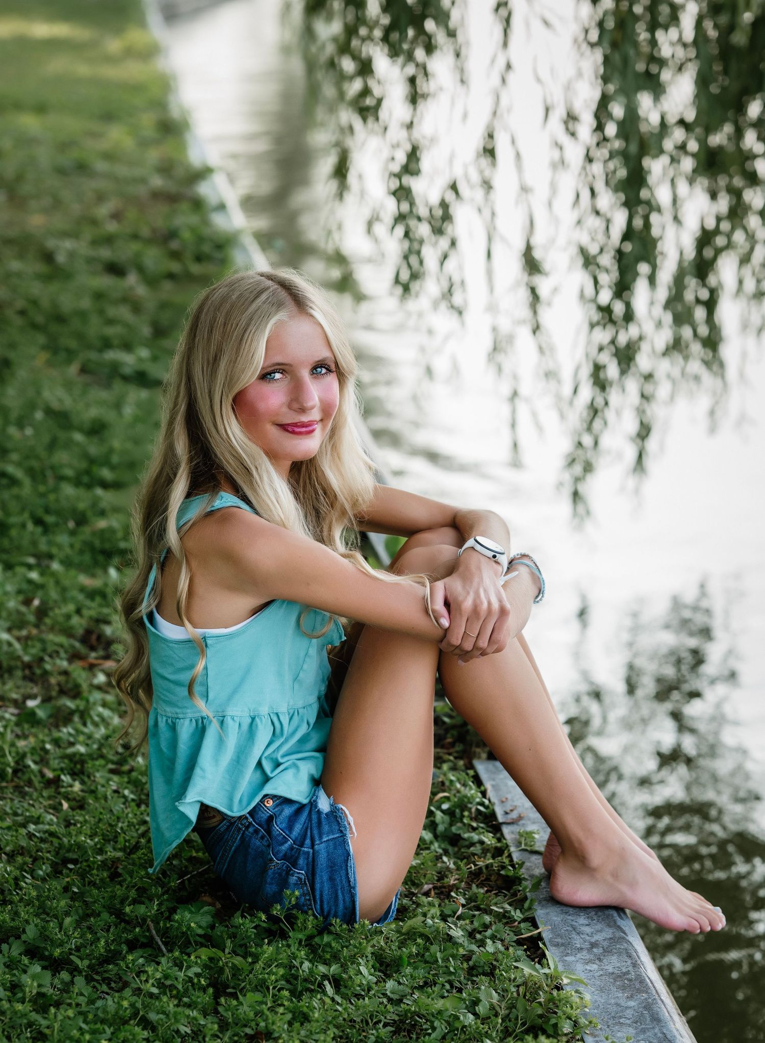 A series of outdoor portrait photos showing someone in a turquoise top sitting by a tranquil pond under weeping willow branches.