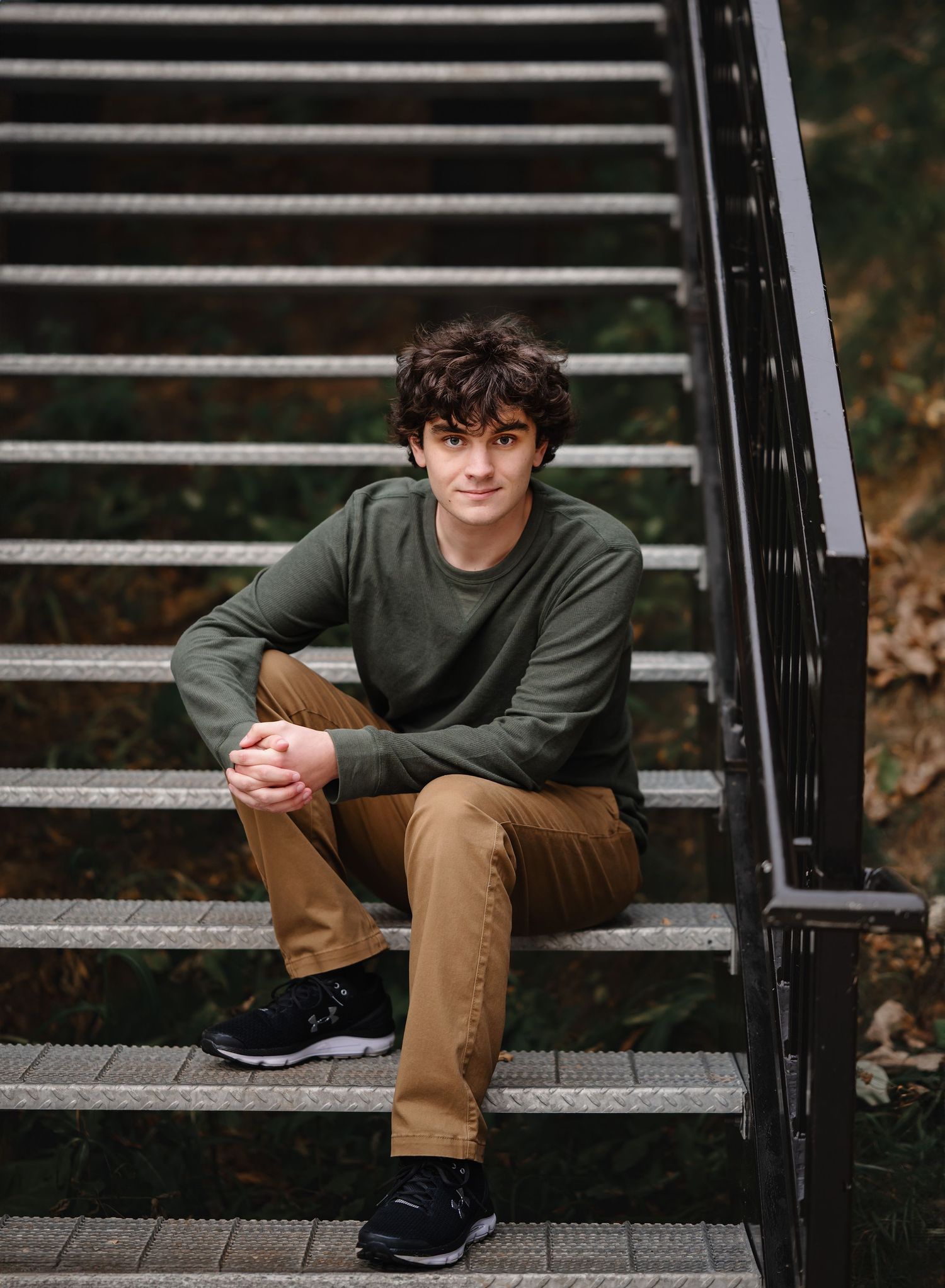 Casual portrait series of someone seated on black steps wearing earth tones.