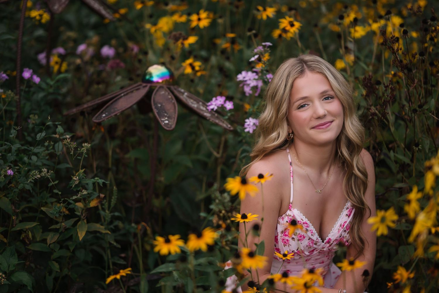 Young blonde woman smiling among colorful wildflowers with a dragonfly in flight beside her.