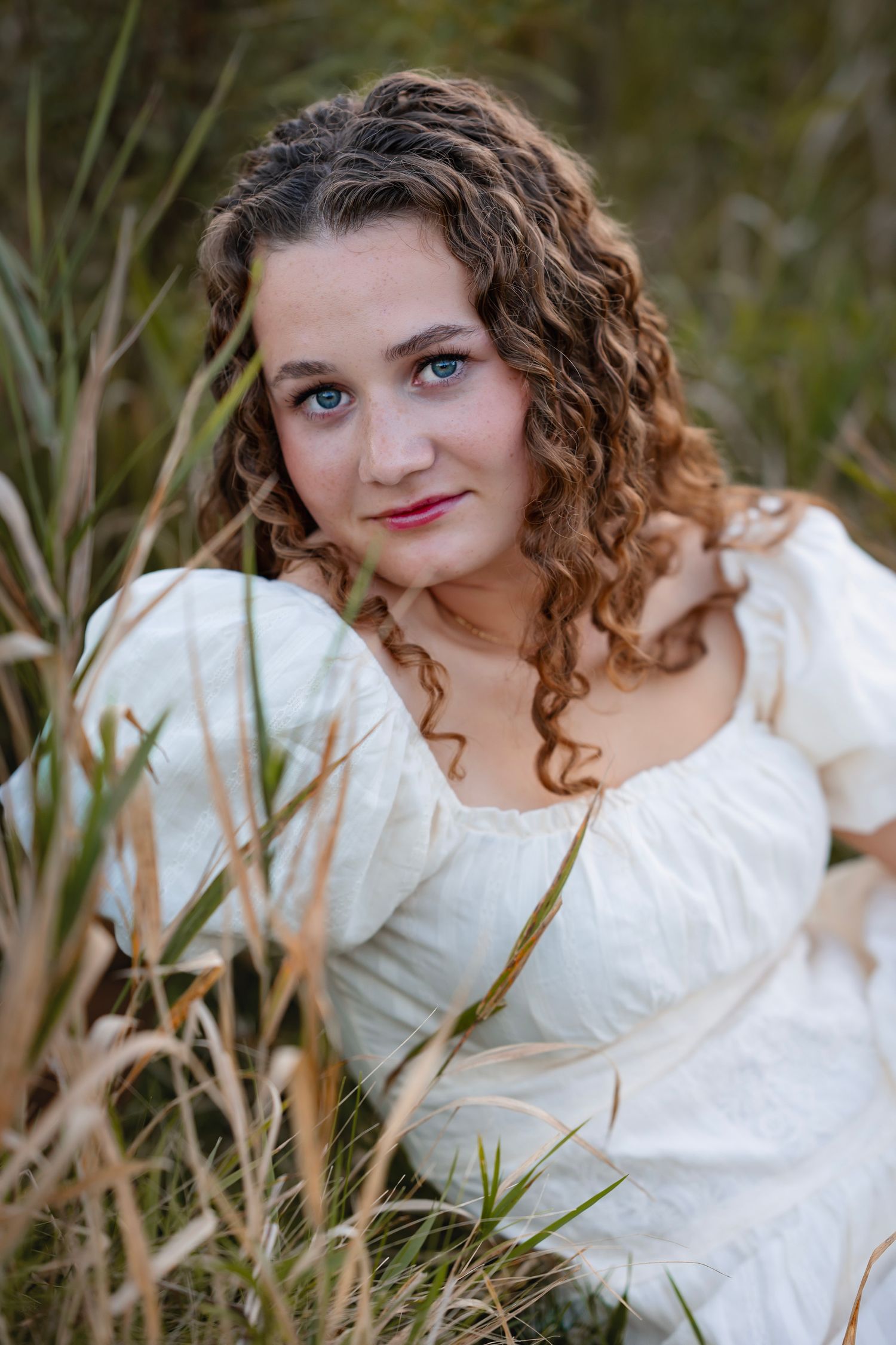 A series of outdoor portrait photos showing someone in a white dress posing among tall grass and natural foliage.