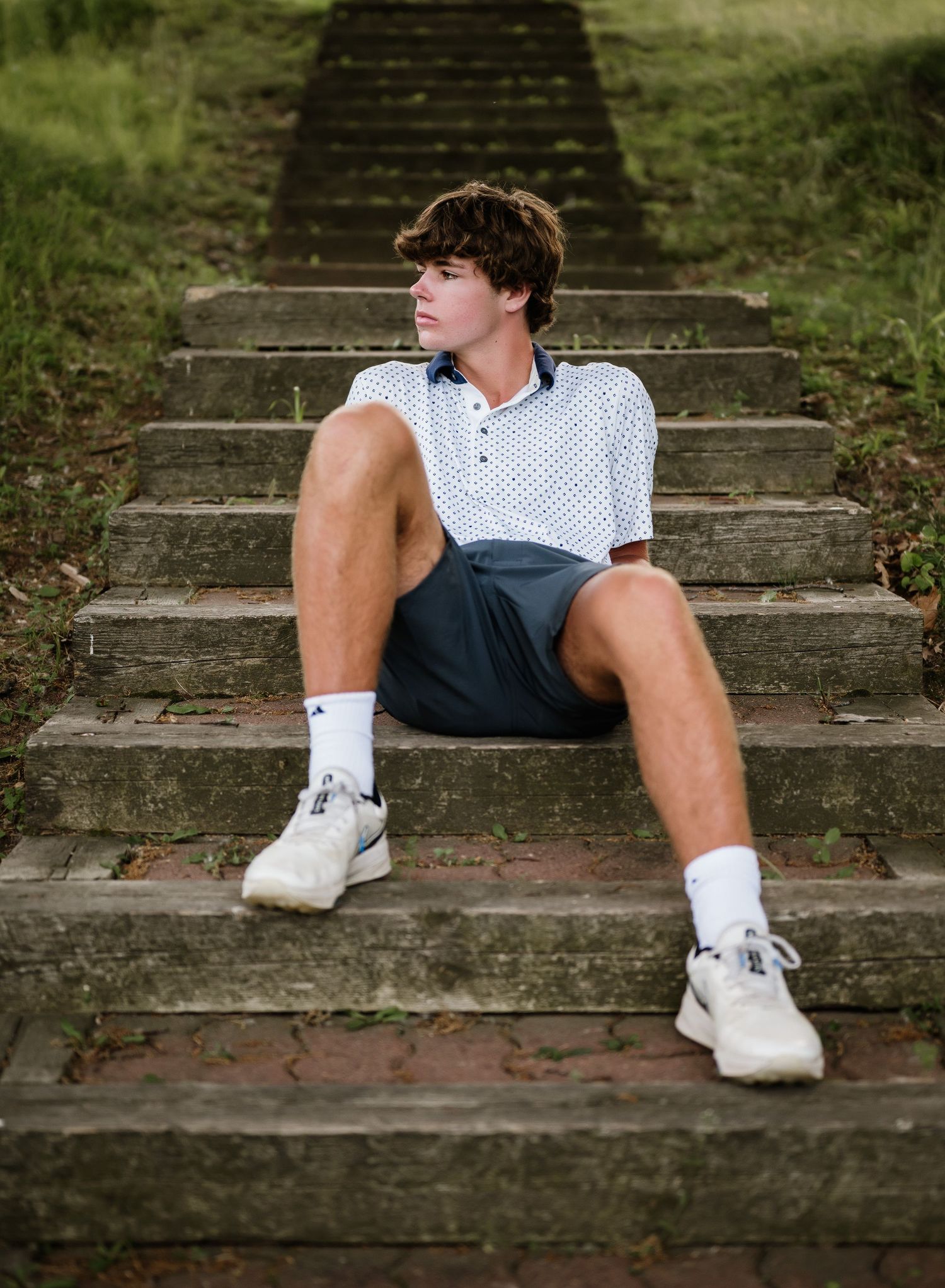 Artistic senior photo series focusing on white sneakers and casual wear while sitting on concrete steps.