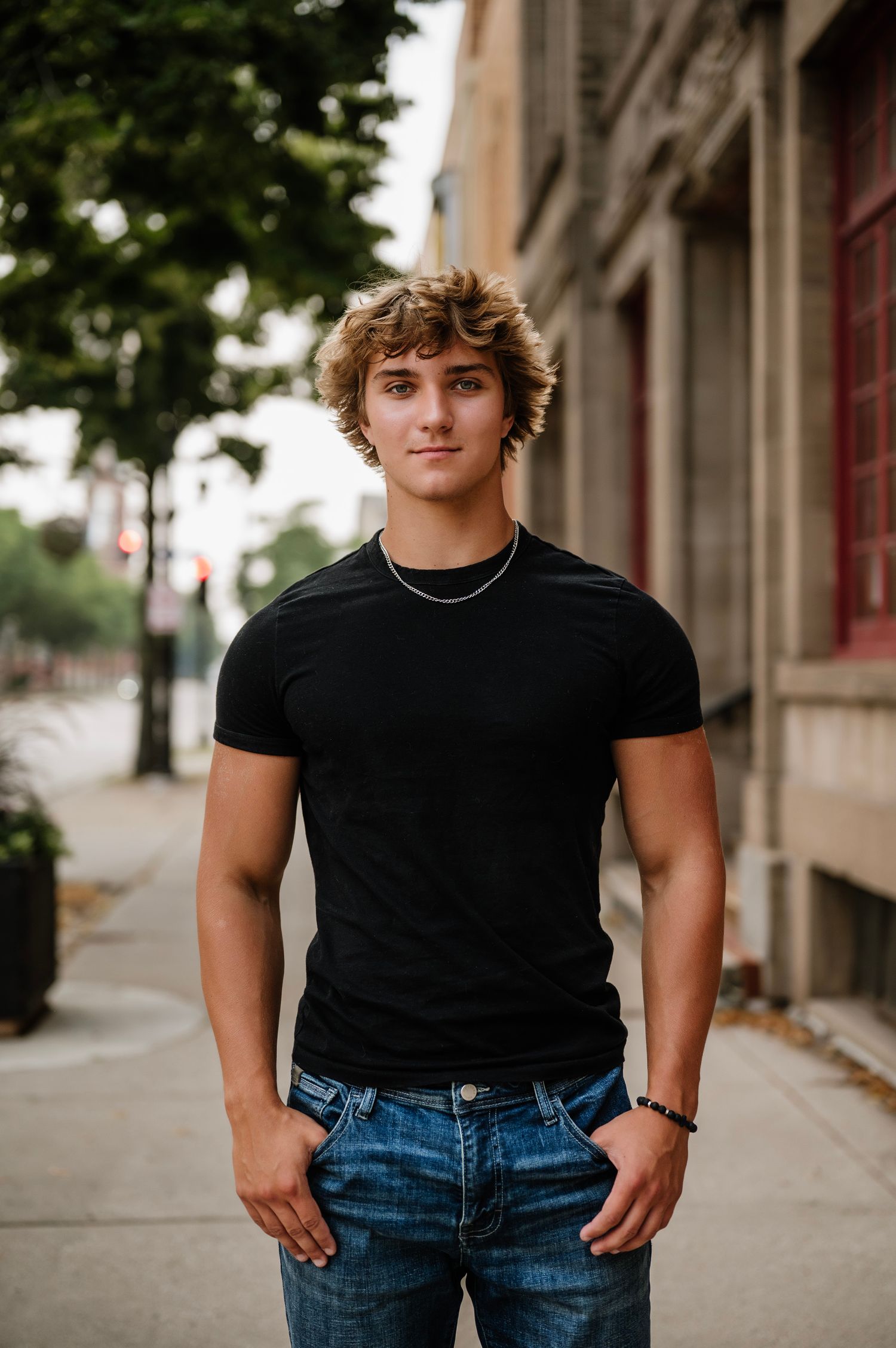 Four casual portraits showing someone wearing a black t-shirt and blue jeans standing on a city sidewalk.