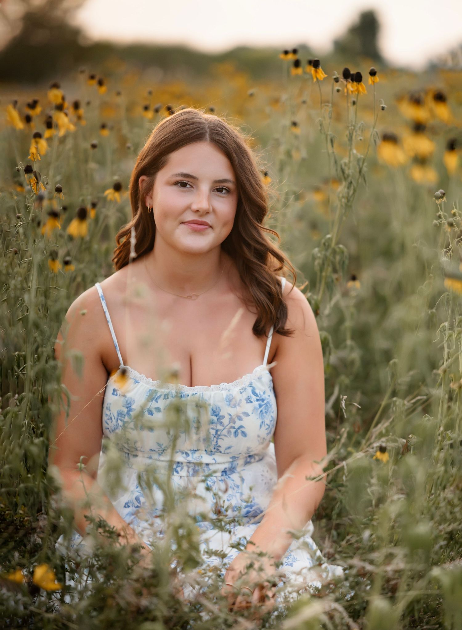 A summer portrait session in a field of yellow wildflowers and tall grass at golden hour.