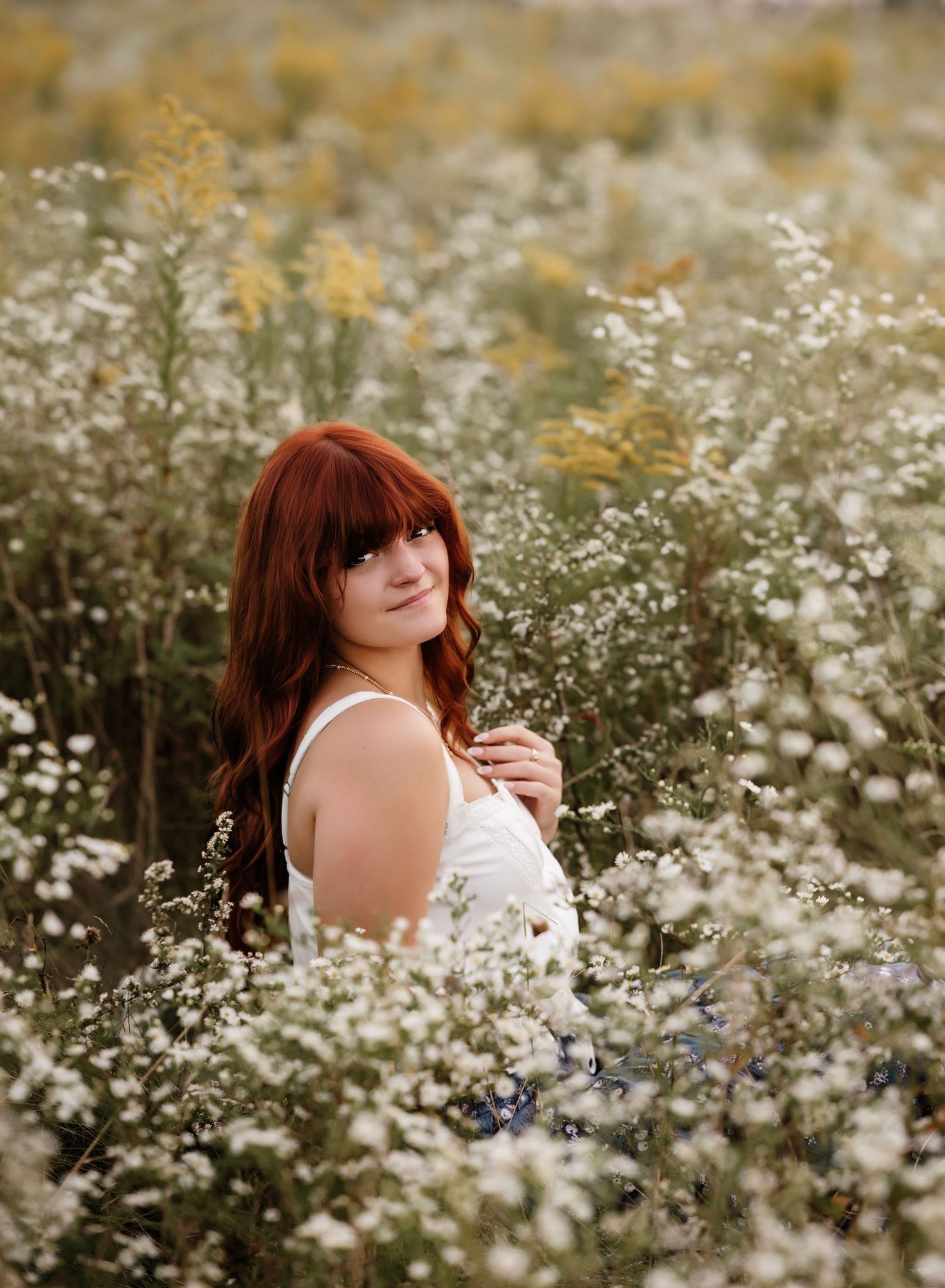A dreamy photoshoot in a field of white wildflowers with soft natural lighting and romantic atmosphere.