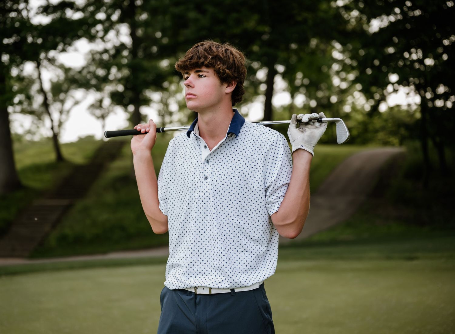 A golfer follows through their swing with their club in hand on a lush green course at sunset.