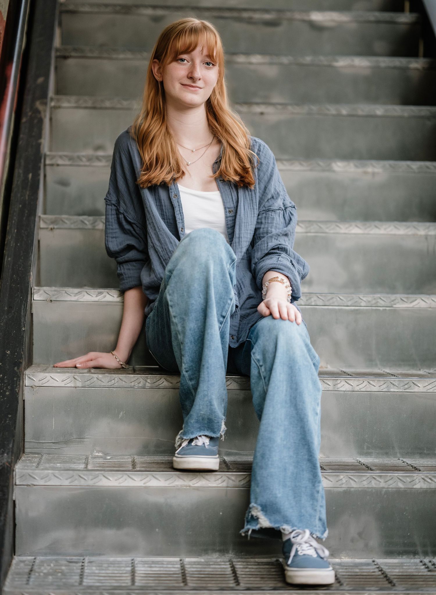 Person in denim and grey attire sits casually on concrete steps in a sequence of four similar poses.
