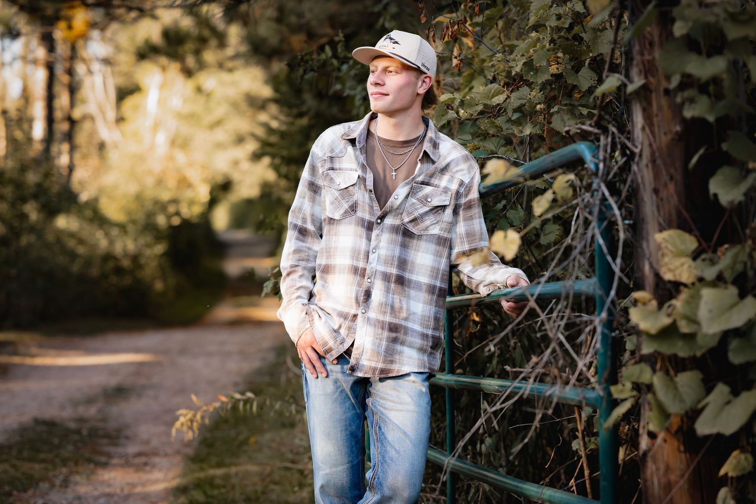 A person in a plaid shirt and jeans leans against a blue bicycle on a wooded autumn path.