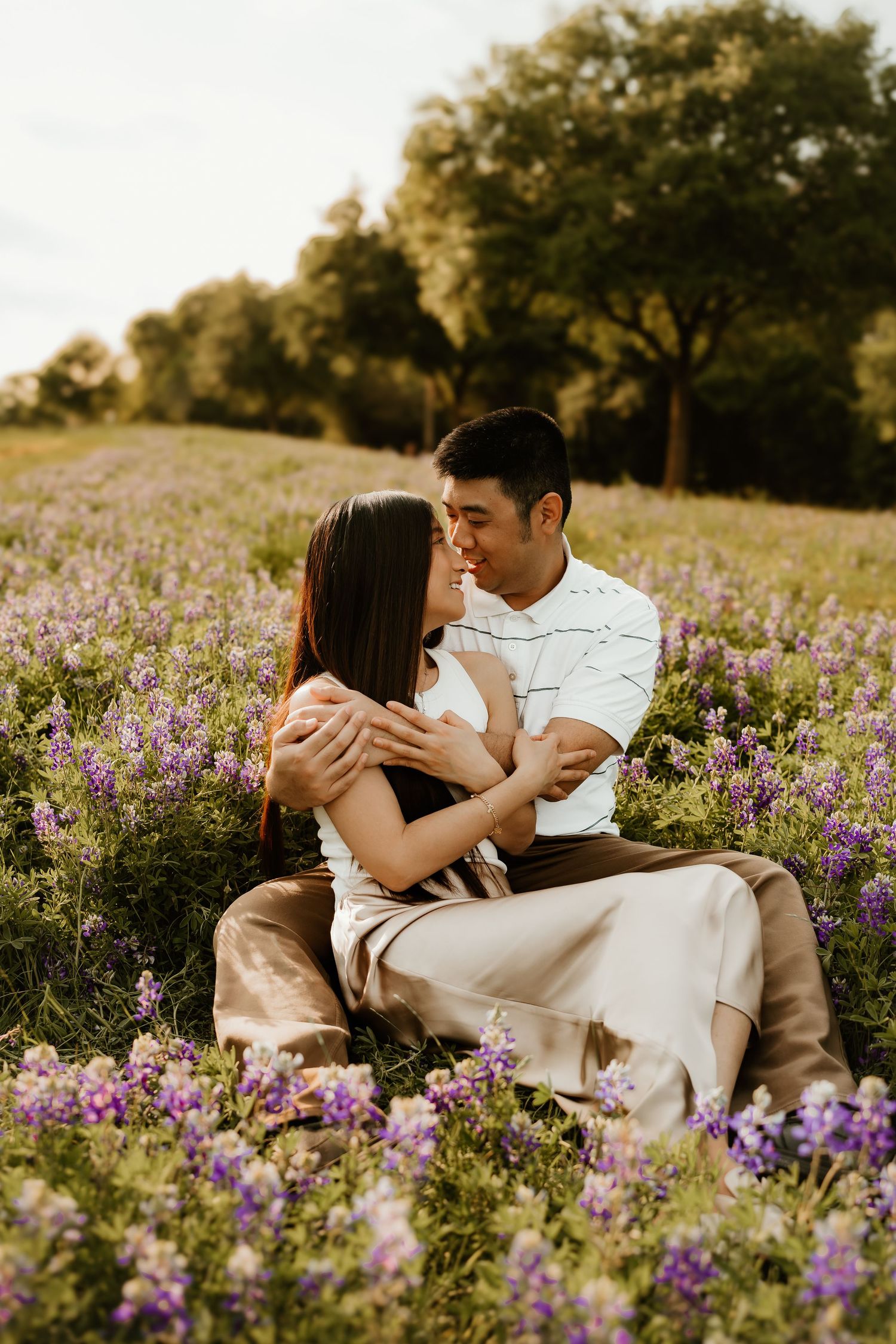 A couple shares romantic moments while lying in a field of purple flowers.