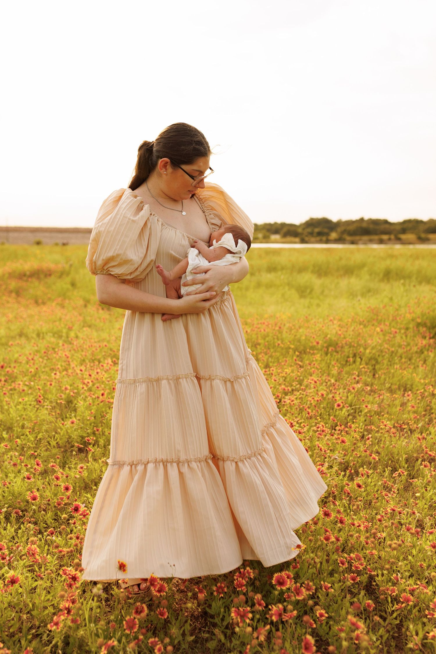 Mother and child share a tender moment in a sunlit field of red wildflowers at golden hour.