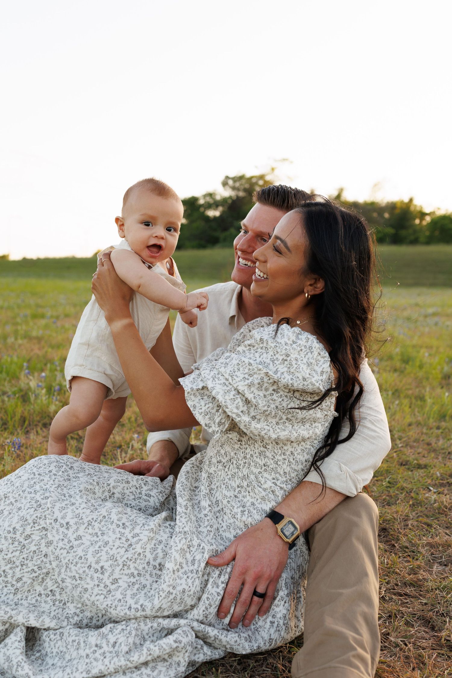 A family enjoying a tender moment together in a sunlit field during golden hour.