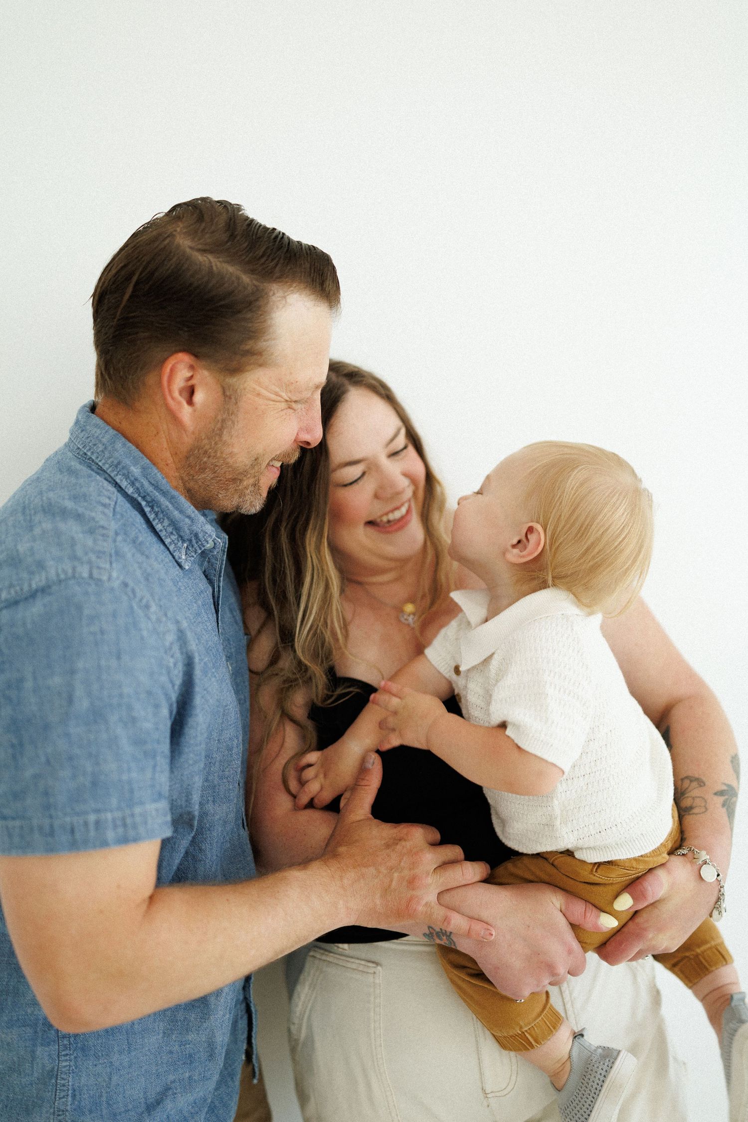 A loving family shares a joyful moment together while dressed casually against a white background.