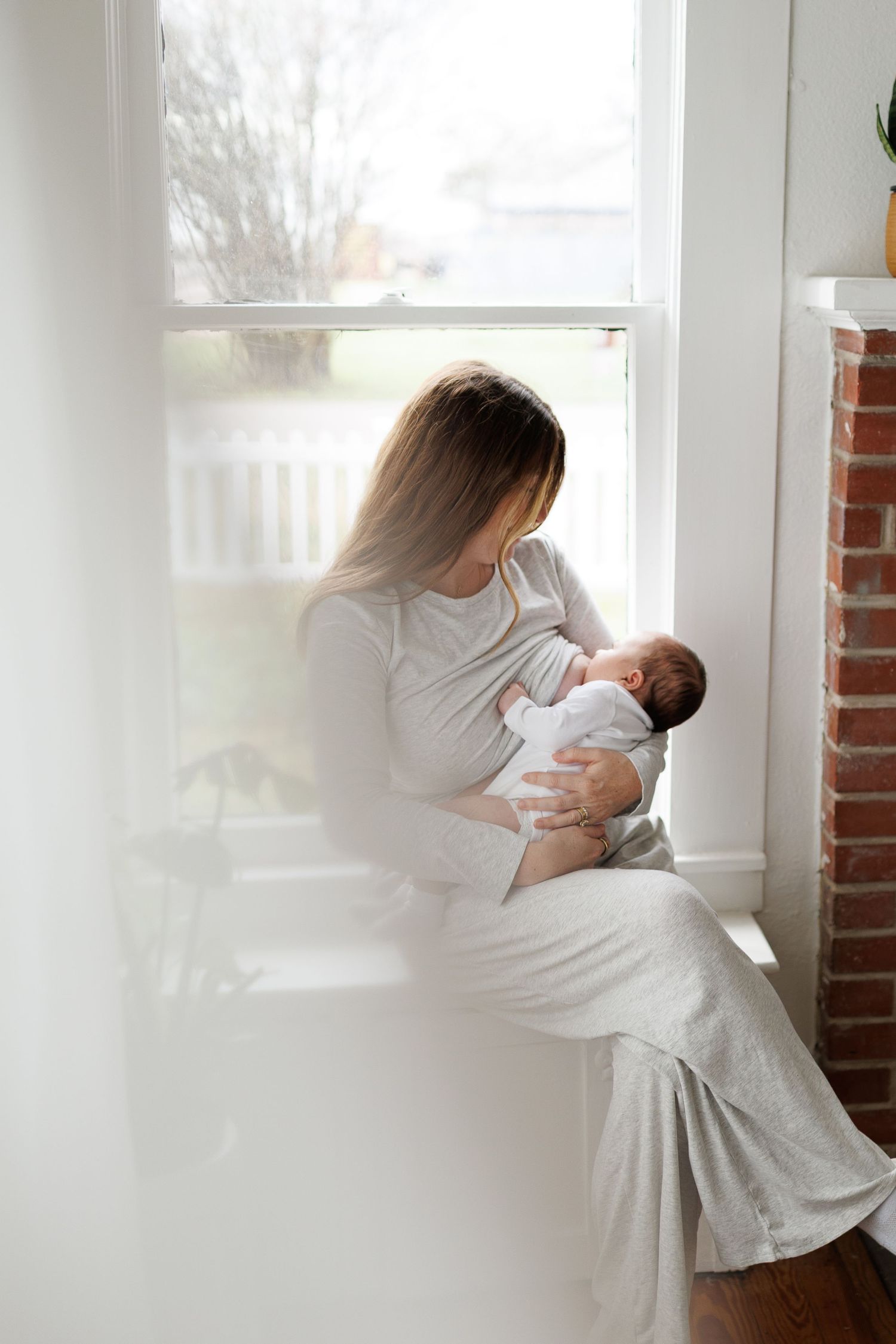 A tender moment captured in a series of soft white photographs by a bright window with natural light streaming in.