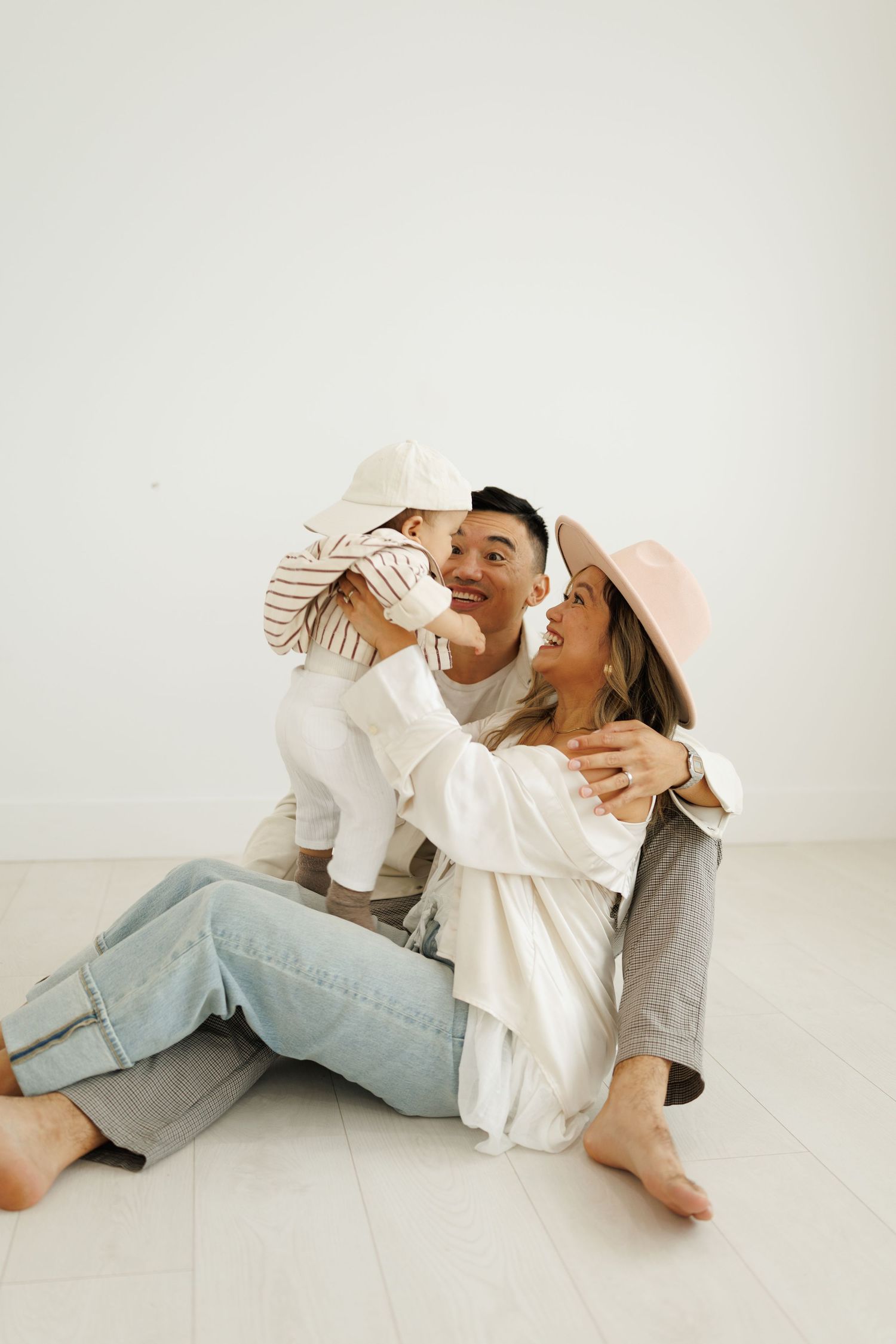 Two people in casual attire playfully interacting while sitting on white floor in series of dynamic poses.