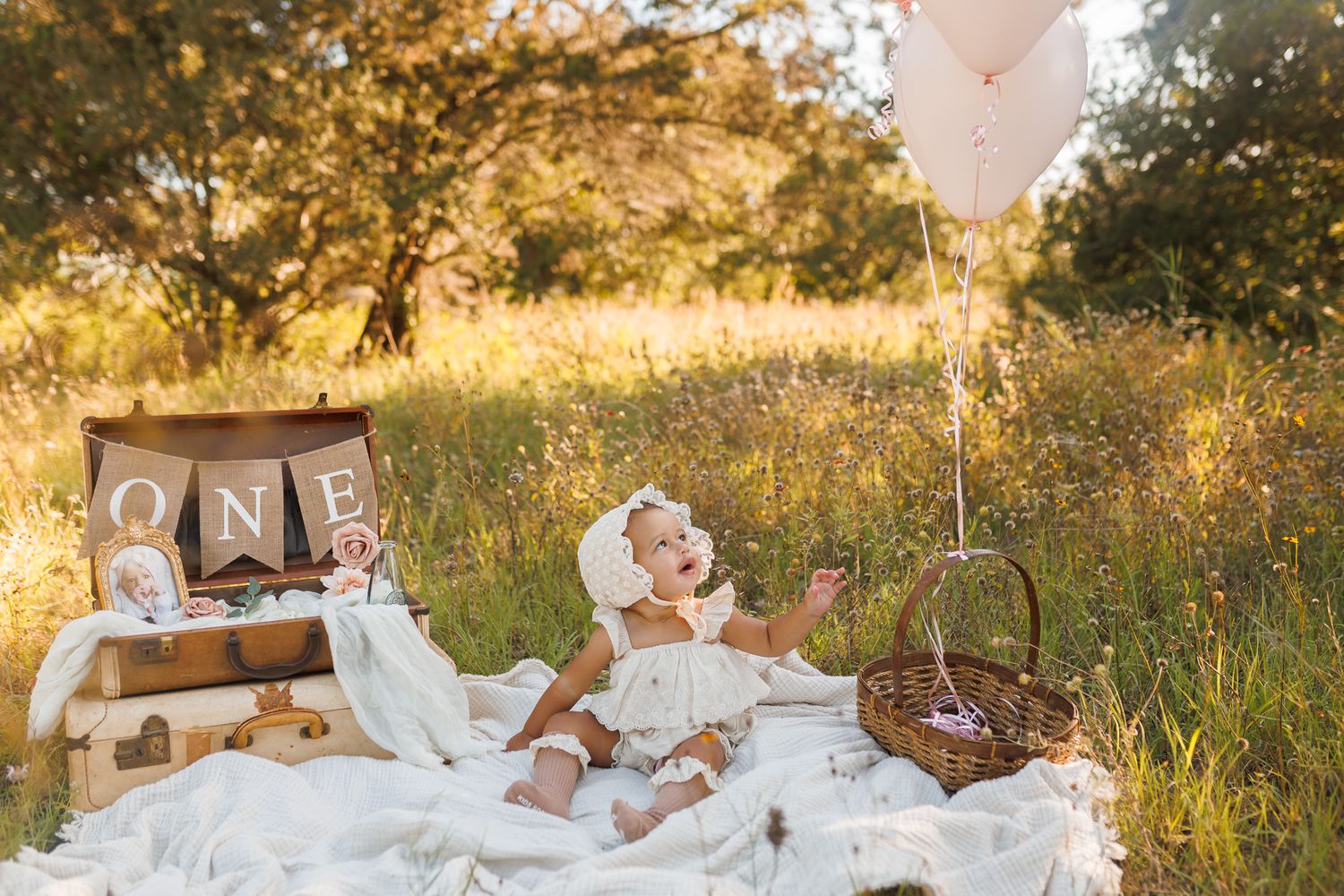 Wedding couple enjoys picnic on vintage blanket in golden sunlit meadow with wine glasses and table settings.
