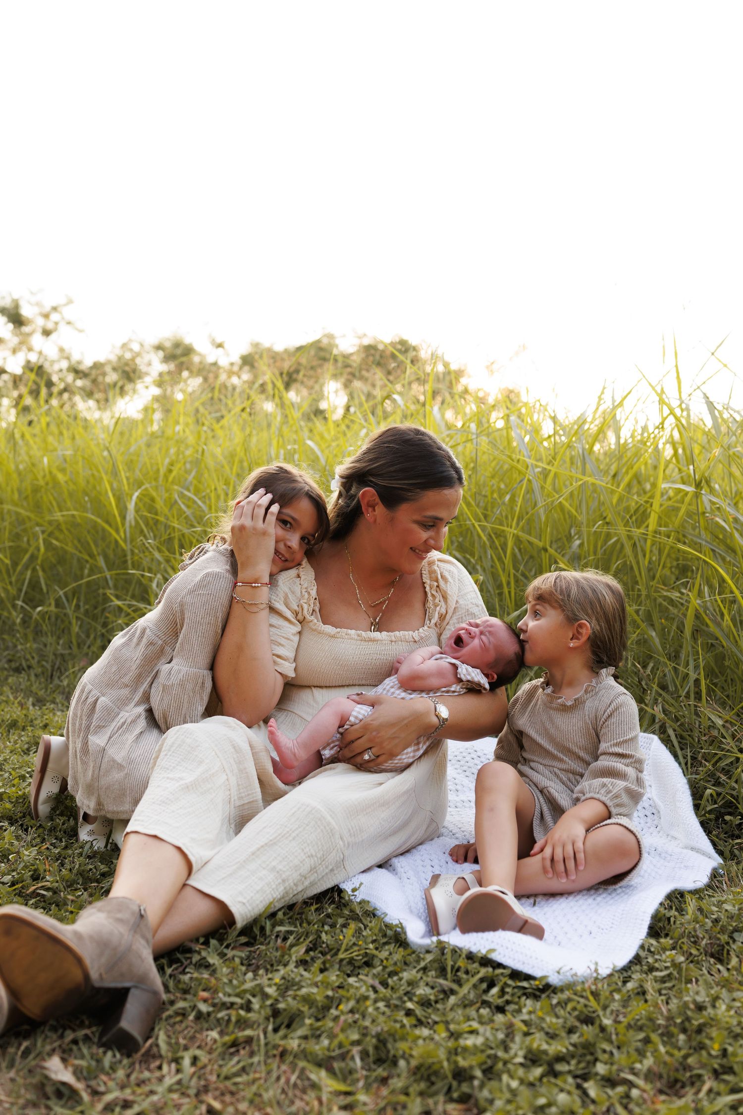 A tender family moment captured in a series of candid photos on grassy field during golden hour.