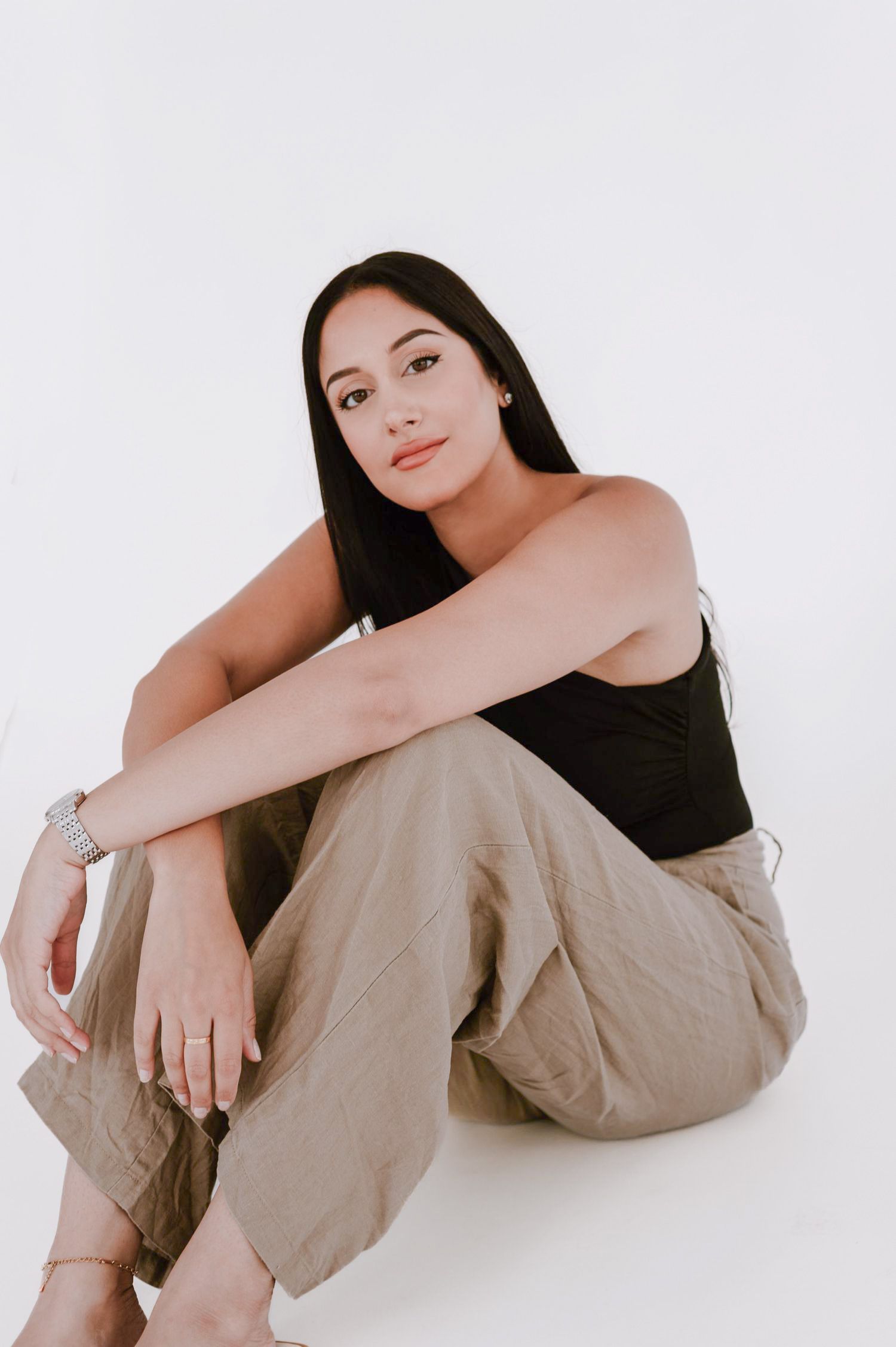 Modern studio portrait of a woman sitting against a minimalist white backdrop. Model headshots