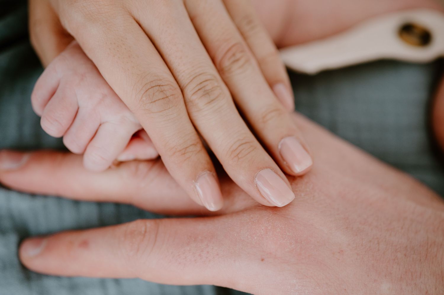 Close-up of intertwined hands, showcasing an engagement ring and soft romantic tones. Family documentary photos