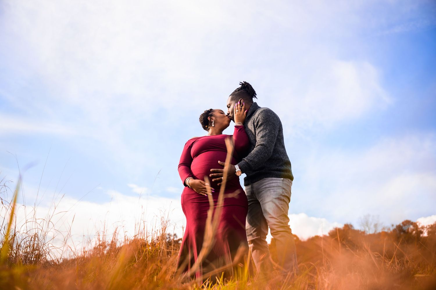 Golden sunset maternity photoshoot in an outdoor field.