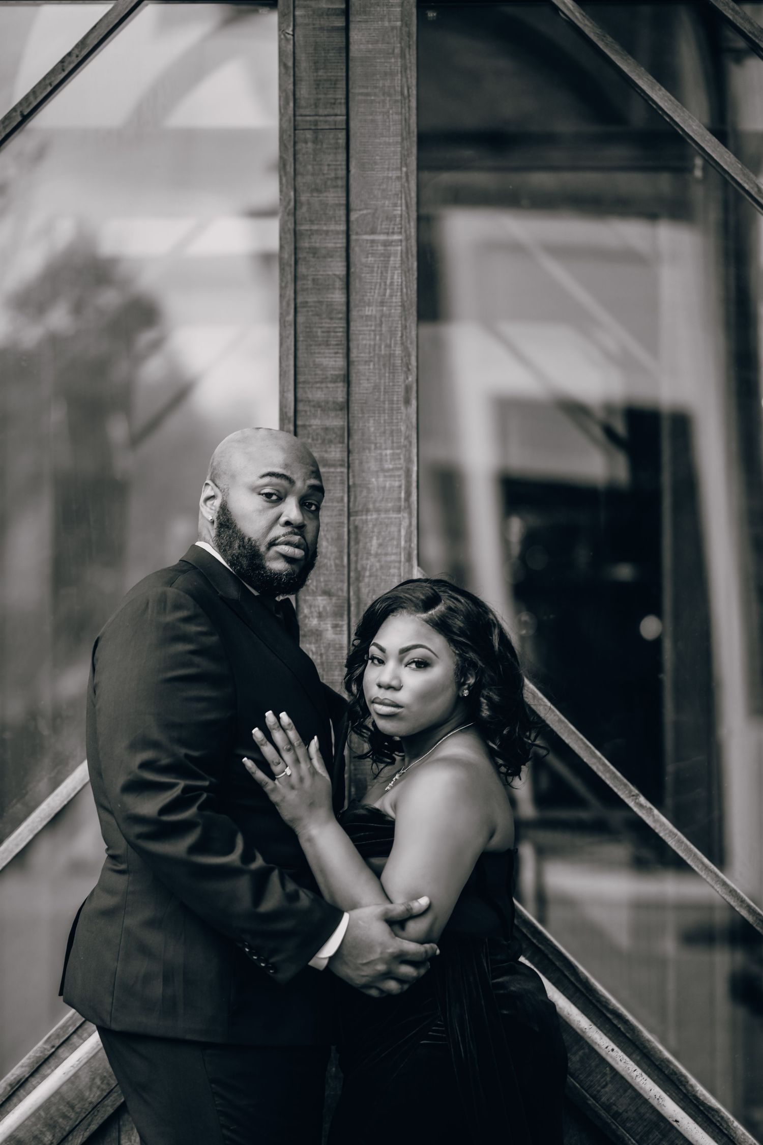 Dramatic black and white portrait of couple posing against architectural elements.