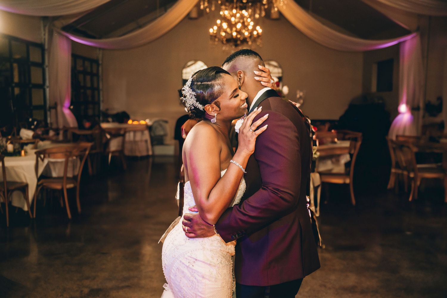 Dancing couple embracing on an elegant ballroom floor under soft lighting and draped decor.