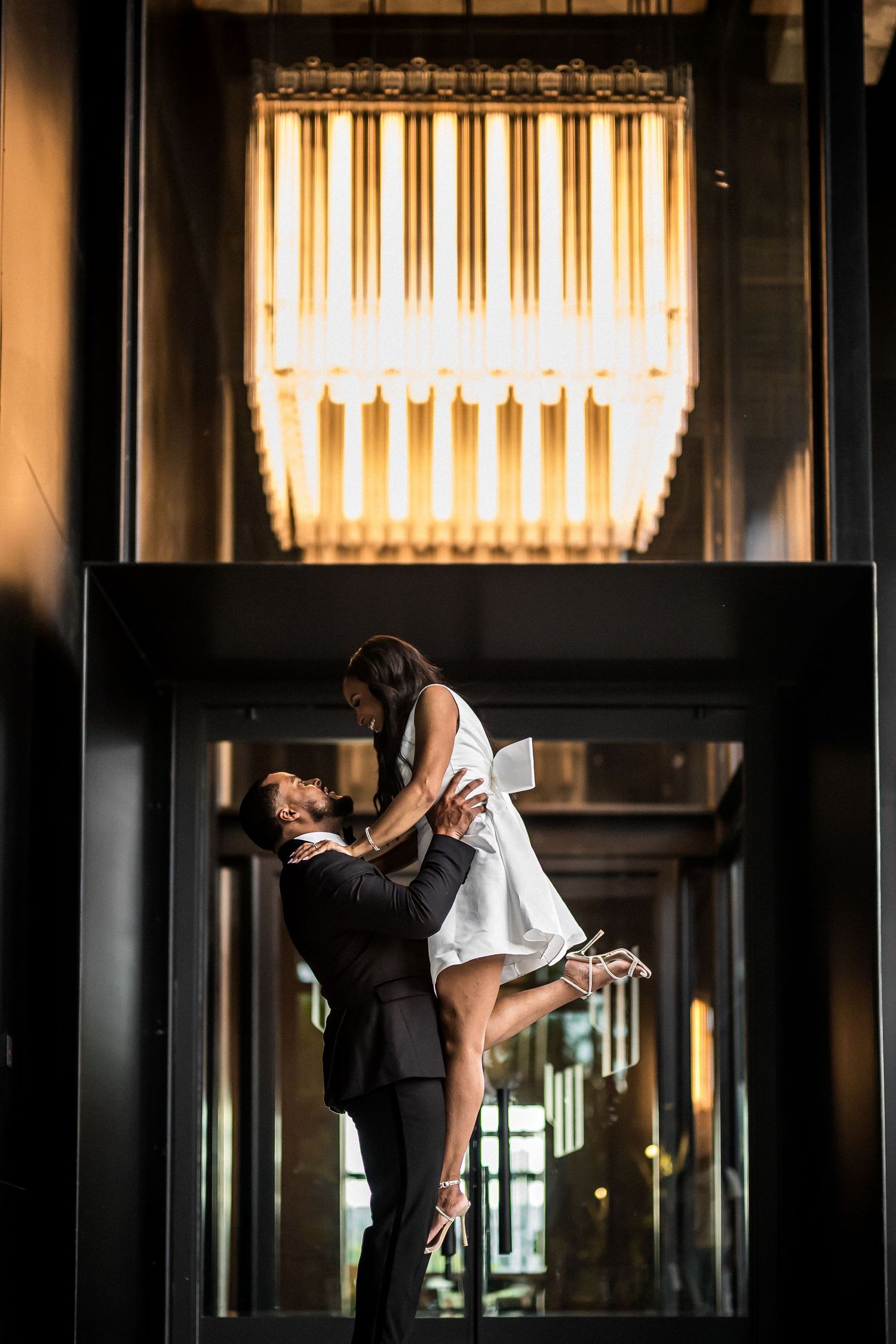Dramatic silhouette of couple dancing against warm backlit windows.
