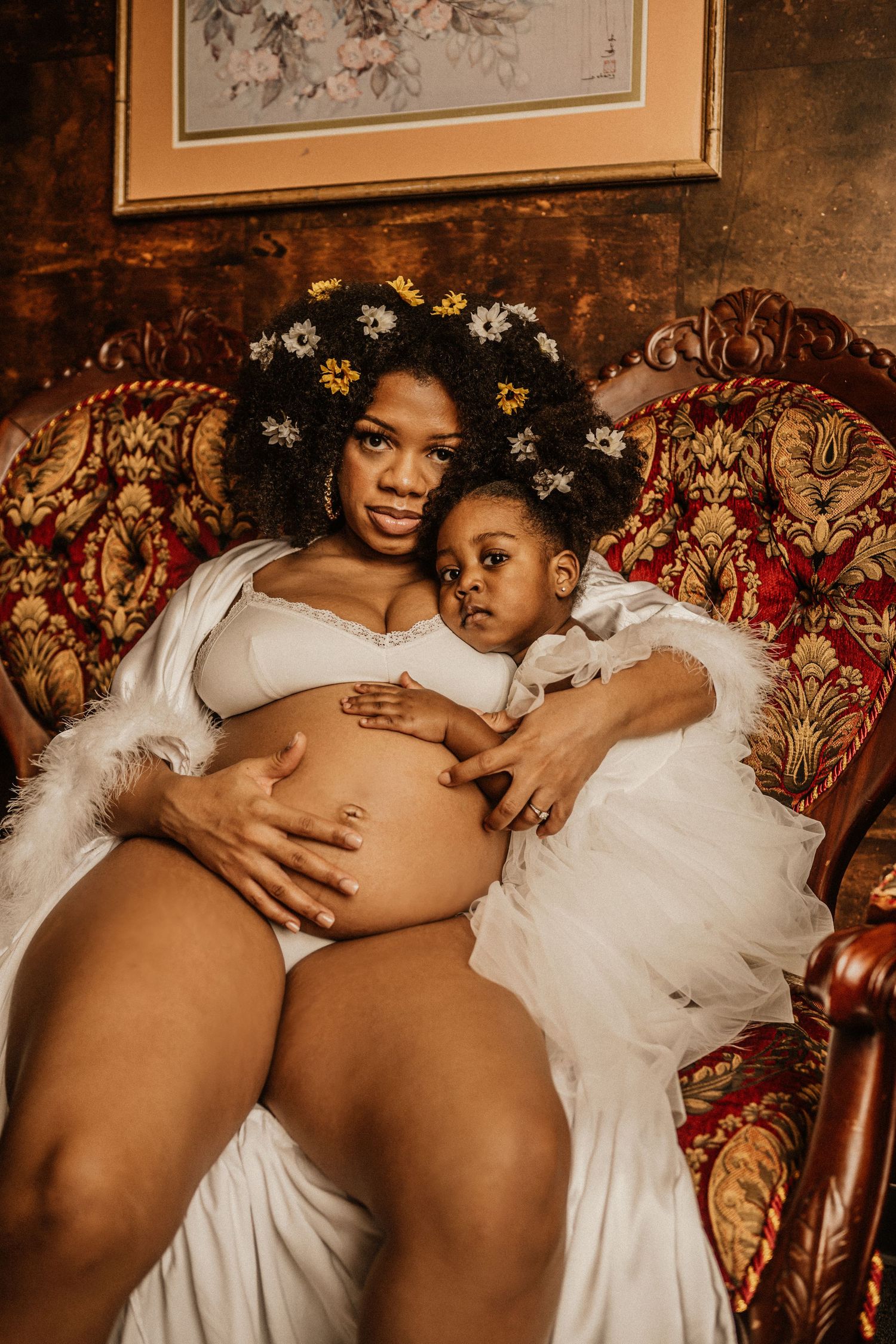 Maternity photography with vintage furniture and floral decorations in warm tones.