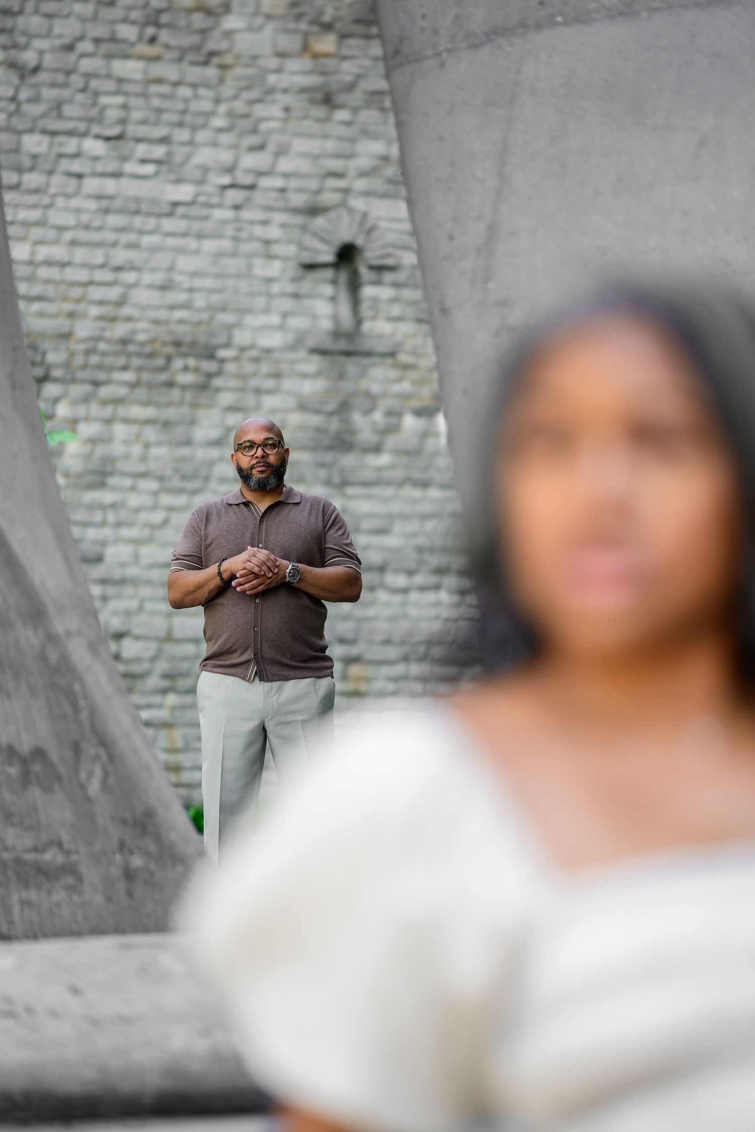 Stone wall and concrete architecture create dramatic backdrop for engagement photos.