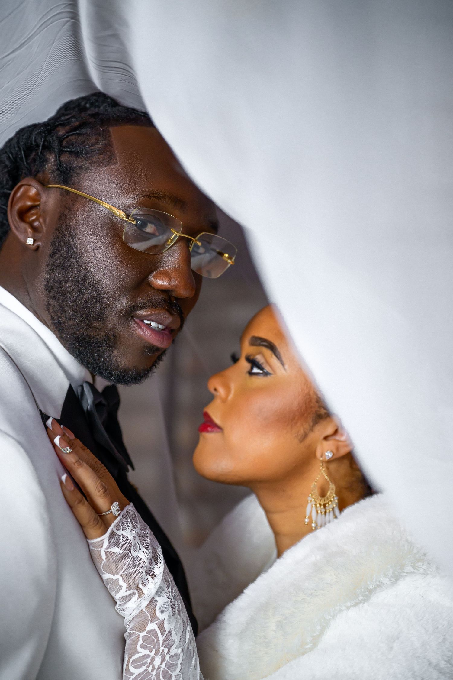 A romantic wedding portrait of a couple in white attire with the bride wearing elegant earrings and makeup.