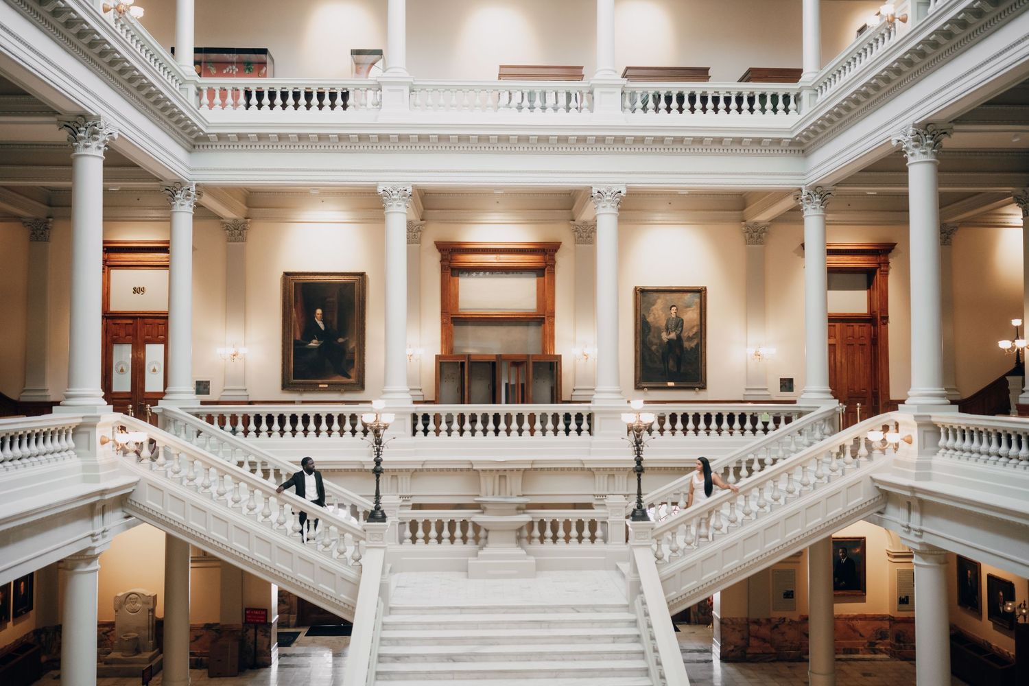 Grand marble staircase in classical building with ornate white balustrades and multiple levels.