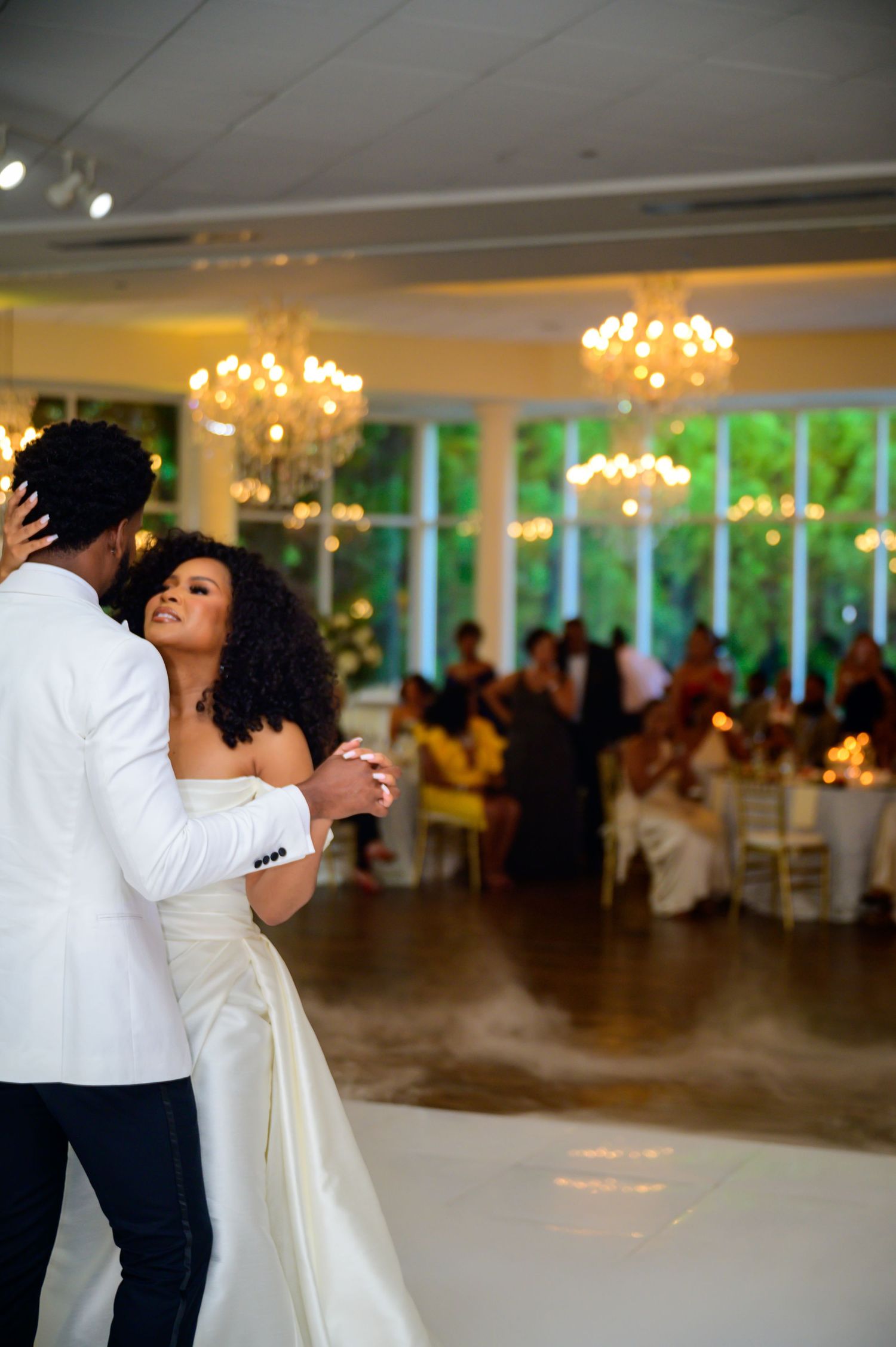 A romantic first dance at a wedding reception with elegant chandeliers and soft lighting.