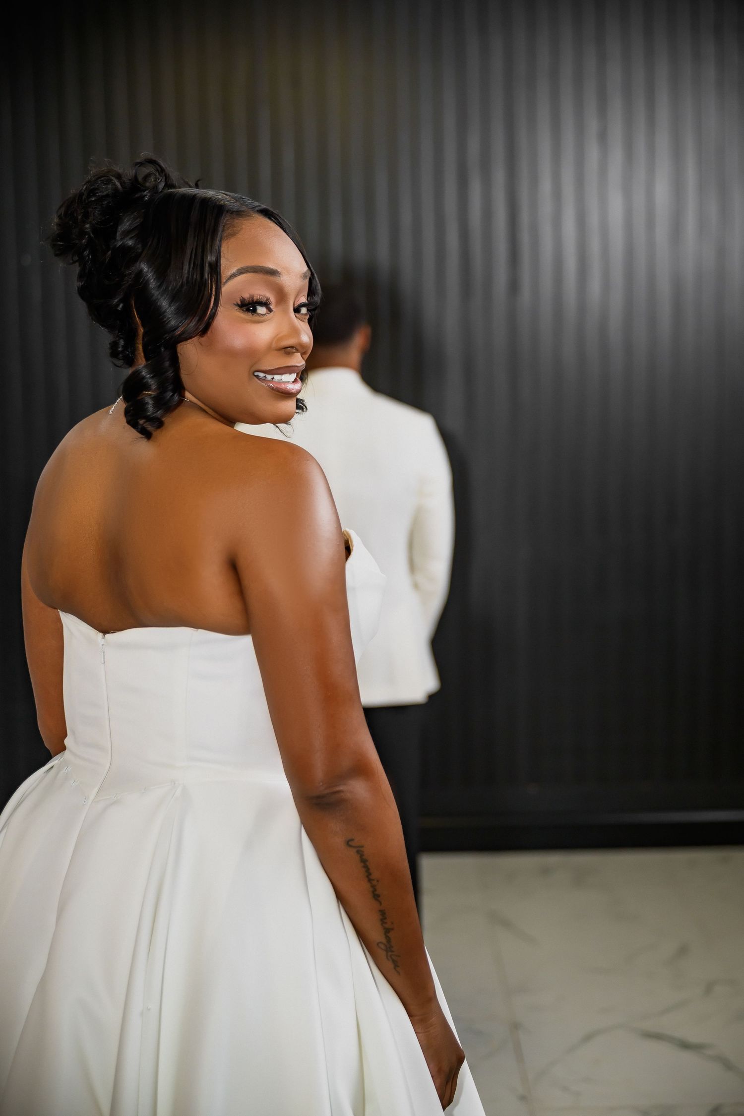 A bride in a strapless white wedding dress smiles joyfully in a series of elegant portraits against a dark background.