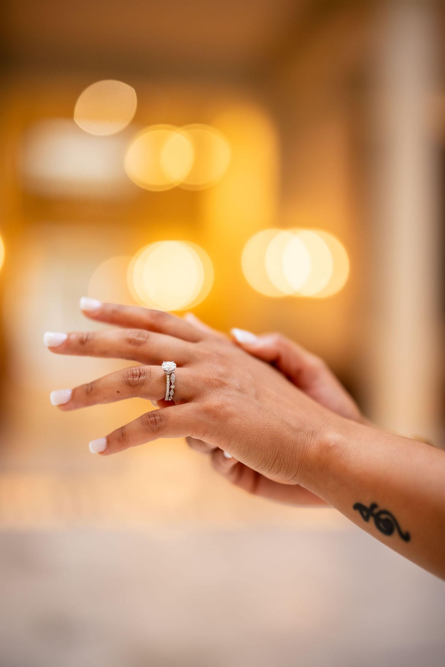 Close-up sequence of hands with a wedding ring making graceful gestures against a warm bokeh background.