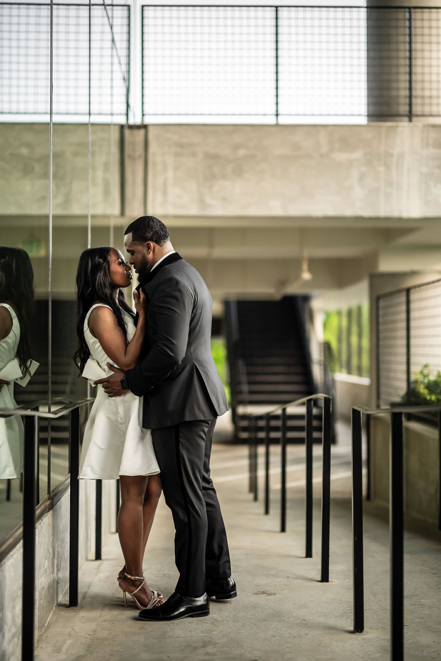 A romantic moment between a couple in formal attire standing in an industrial-style hallway.