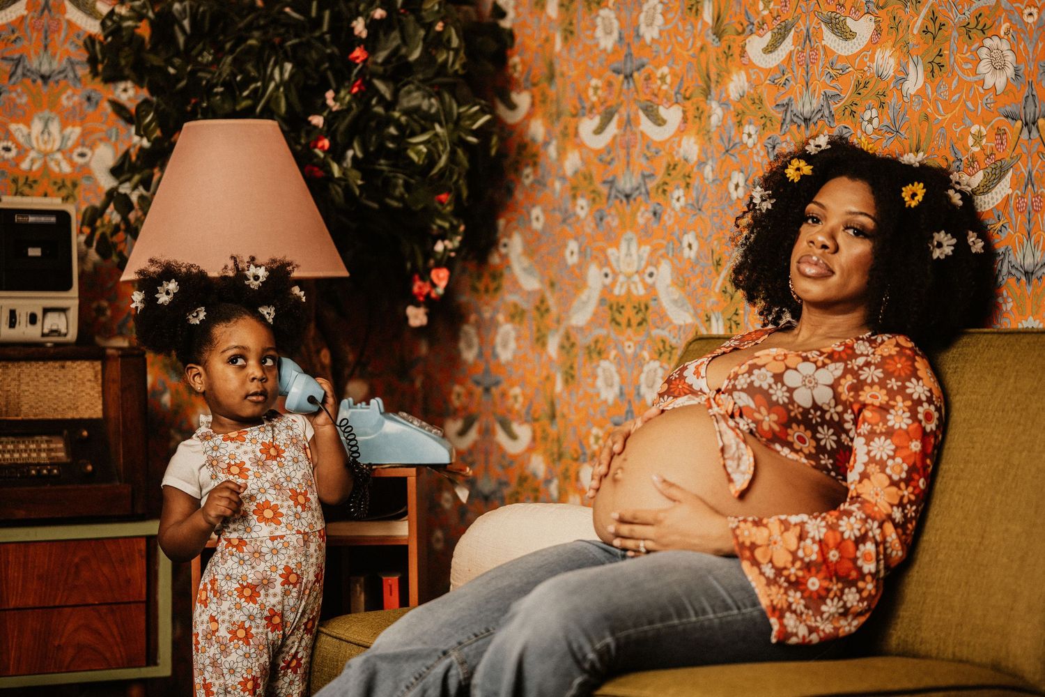A cozy indoor photoshoot featuring warm lighting and floral wallpaper creating an intimate atmosphere.
