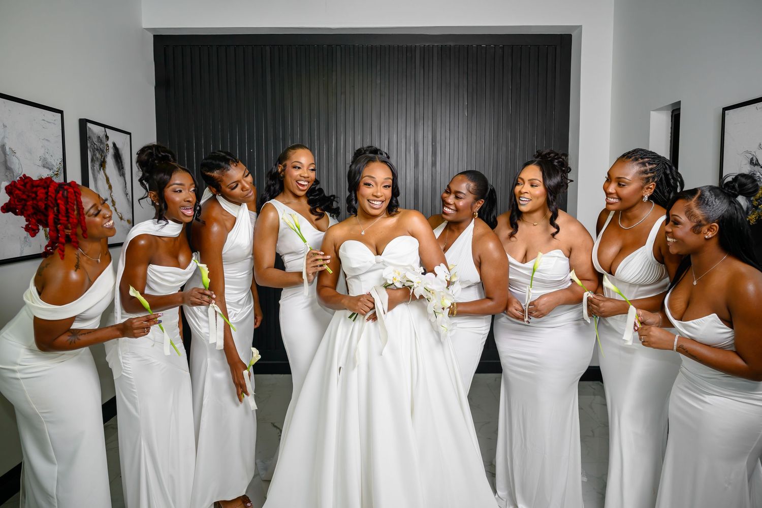 A group wearing matching white formal dresses pose together in a celebratory moment at a wedding event.