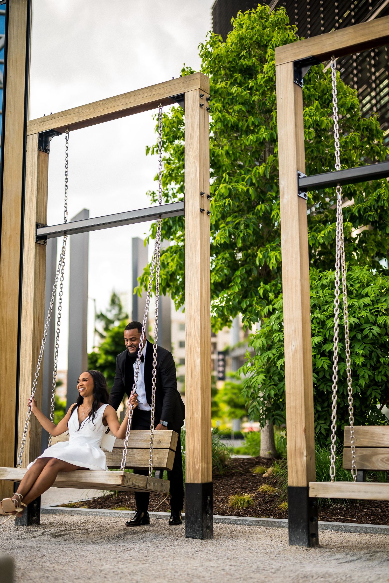 Couple sits together on wooden swings in modern outdoor setting.