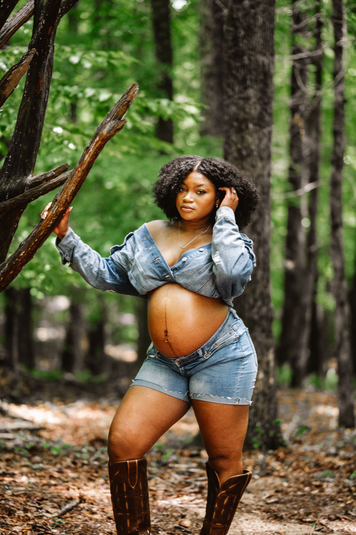 Maternity photoshoot in a forest setting with denim jacket.
