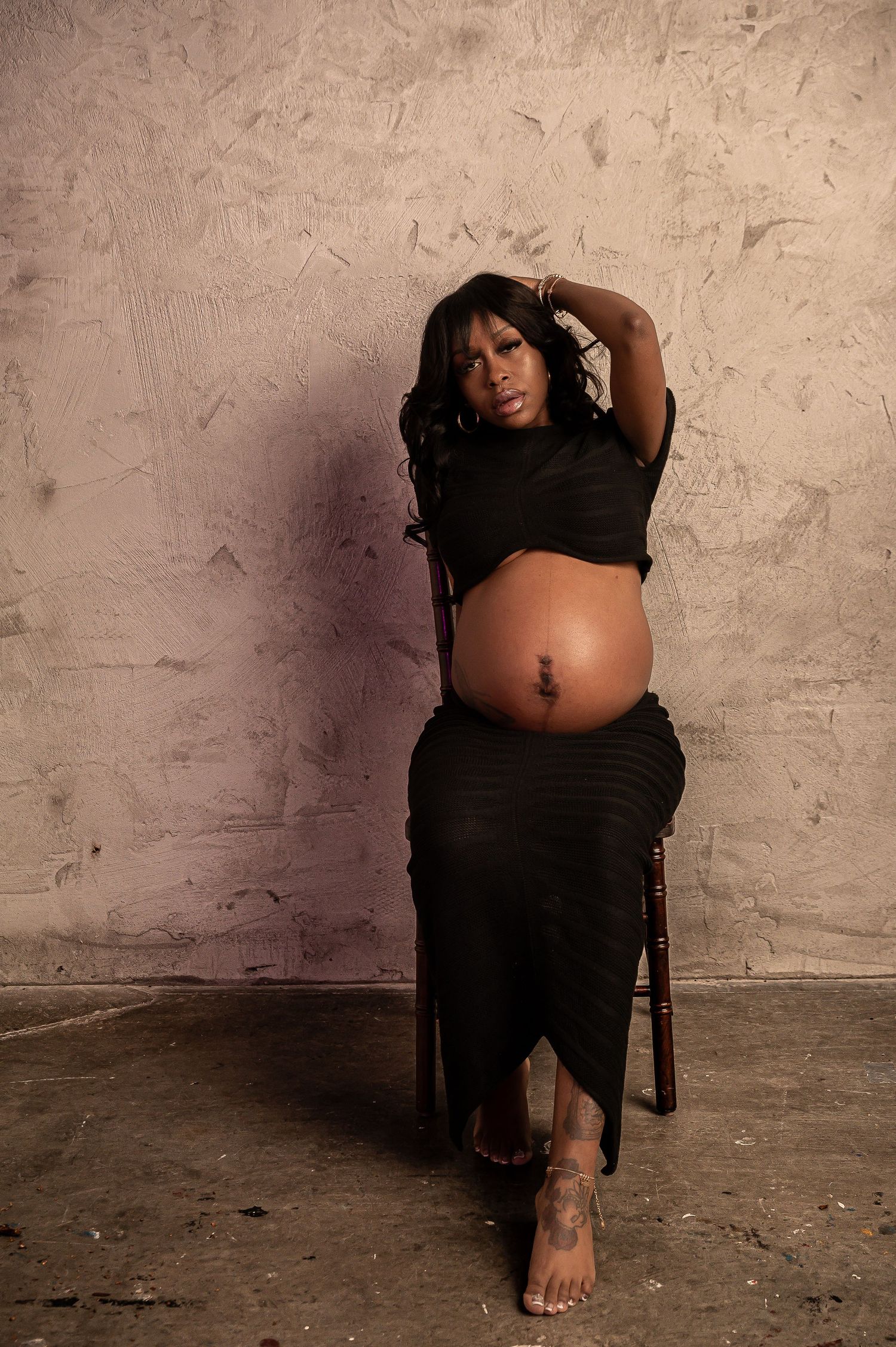 Intimate maternity portrait in minimalist studio setting.
