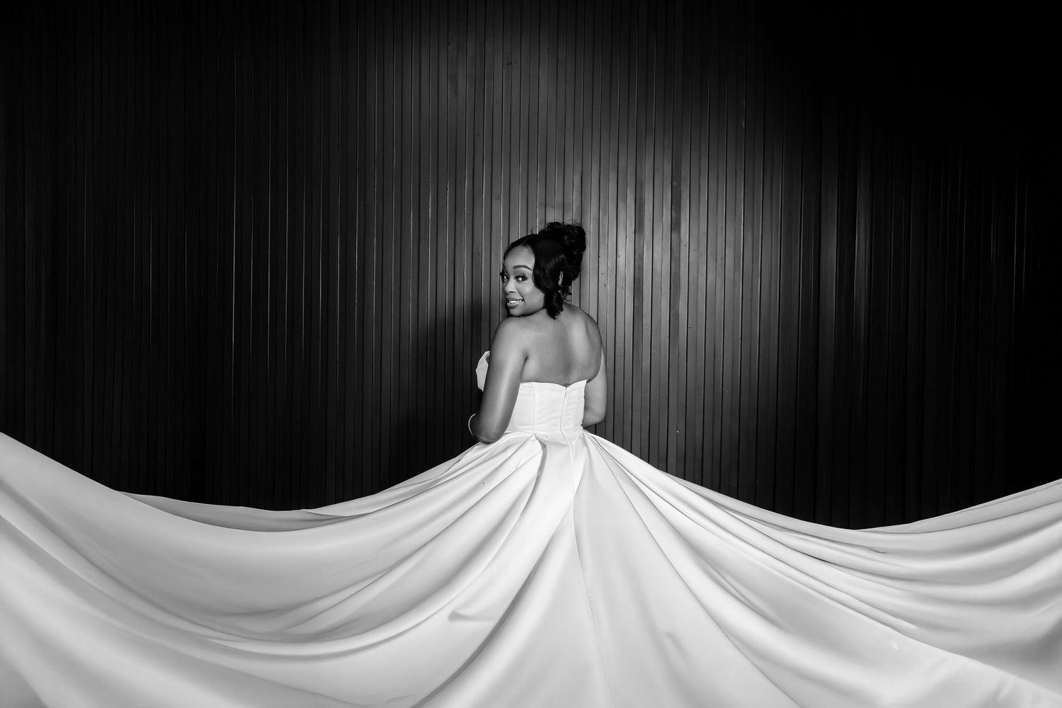 A dramatic black and white photo shows a person in a flowing white wedding gown creating a sweeping silhouette.