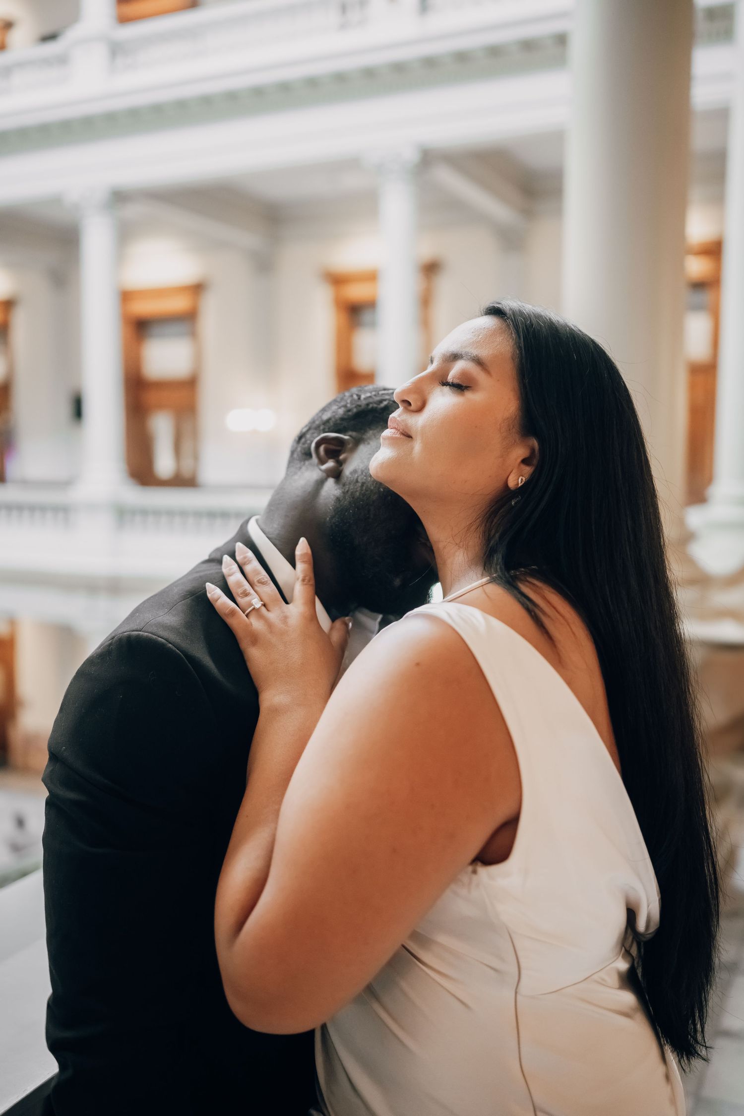 Romantic moment between couple on marble staircase during wedding photoshoot.