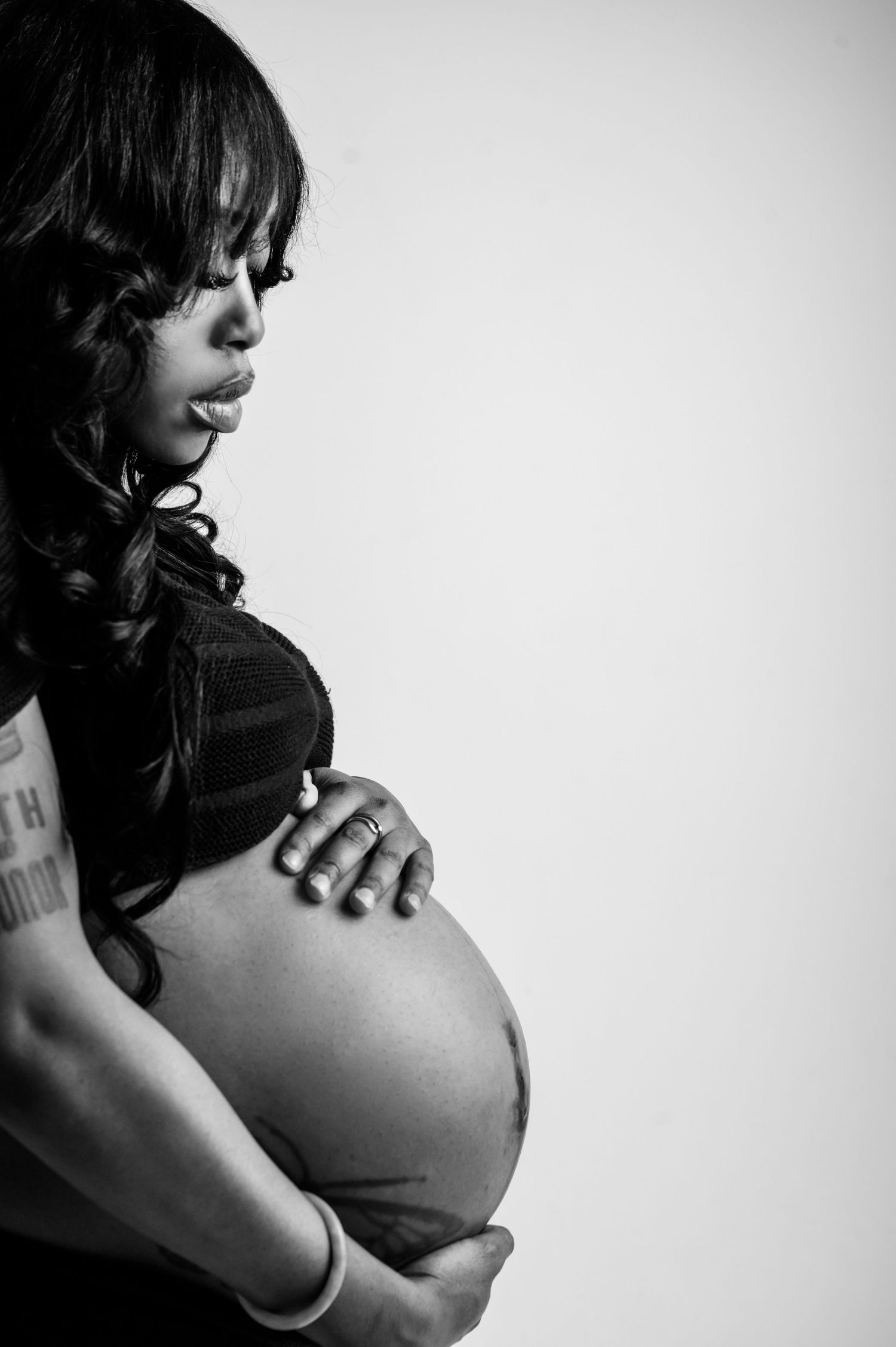 Artistic black and white maternity portrait with dramatic lighting.