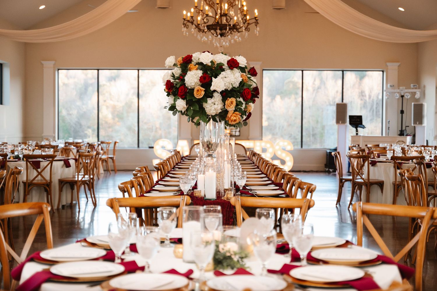 Spacious wedding venue with floor-to-ceiling windows, wooden chairs, and long dining tables.