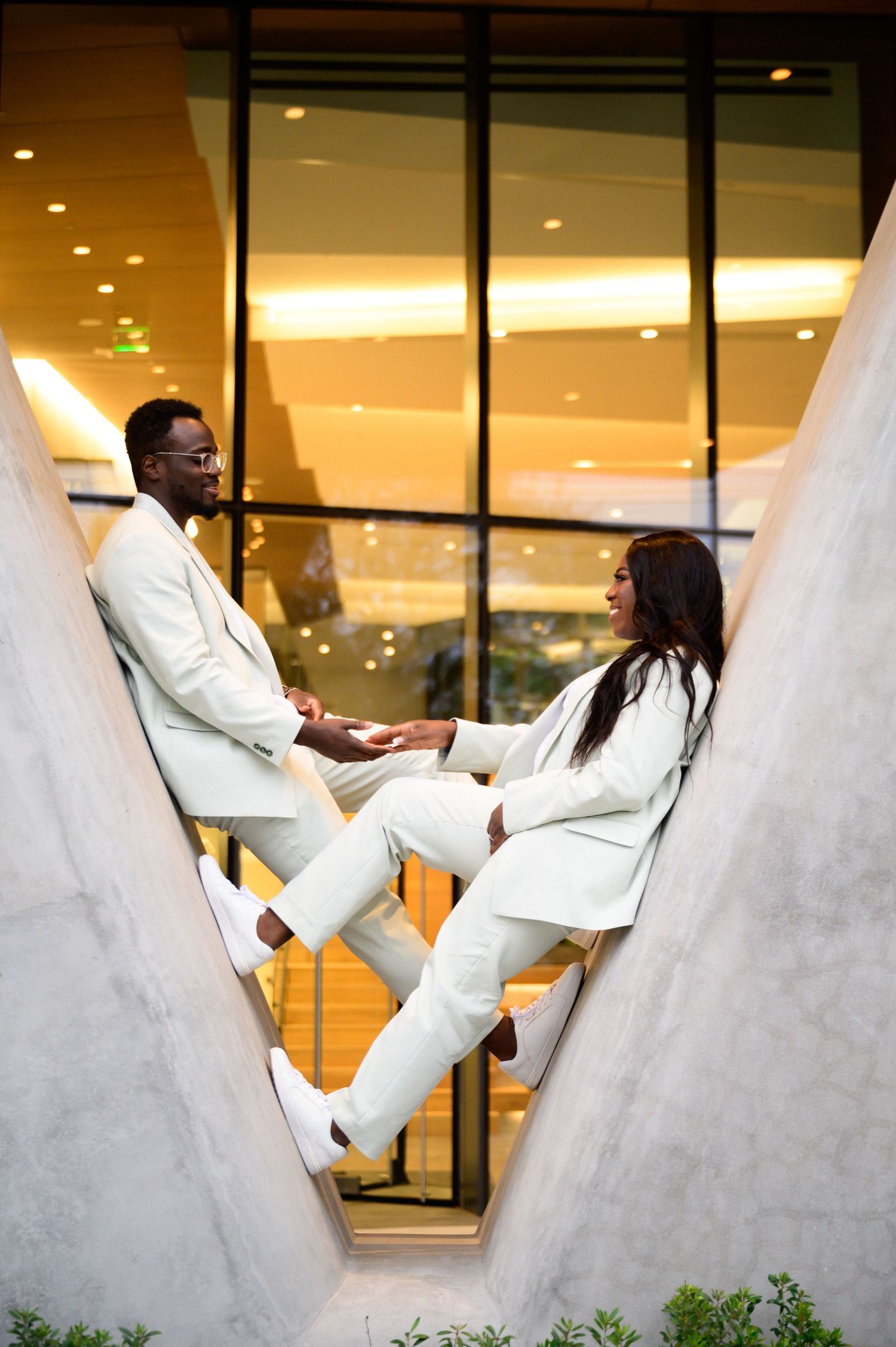 Playful sequence showing movement and dance against modern architecture in white formal wear.